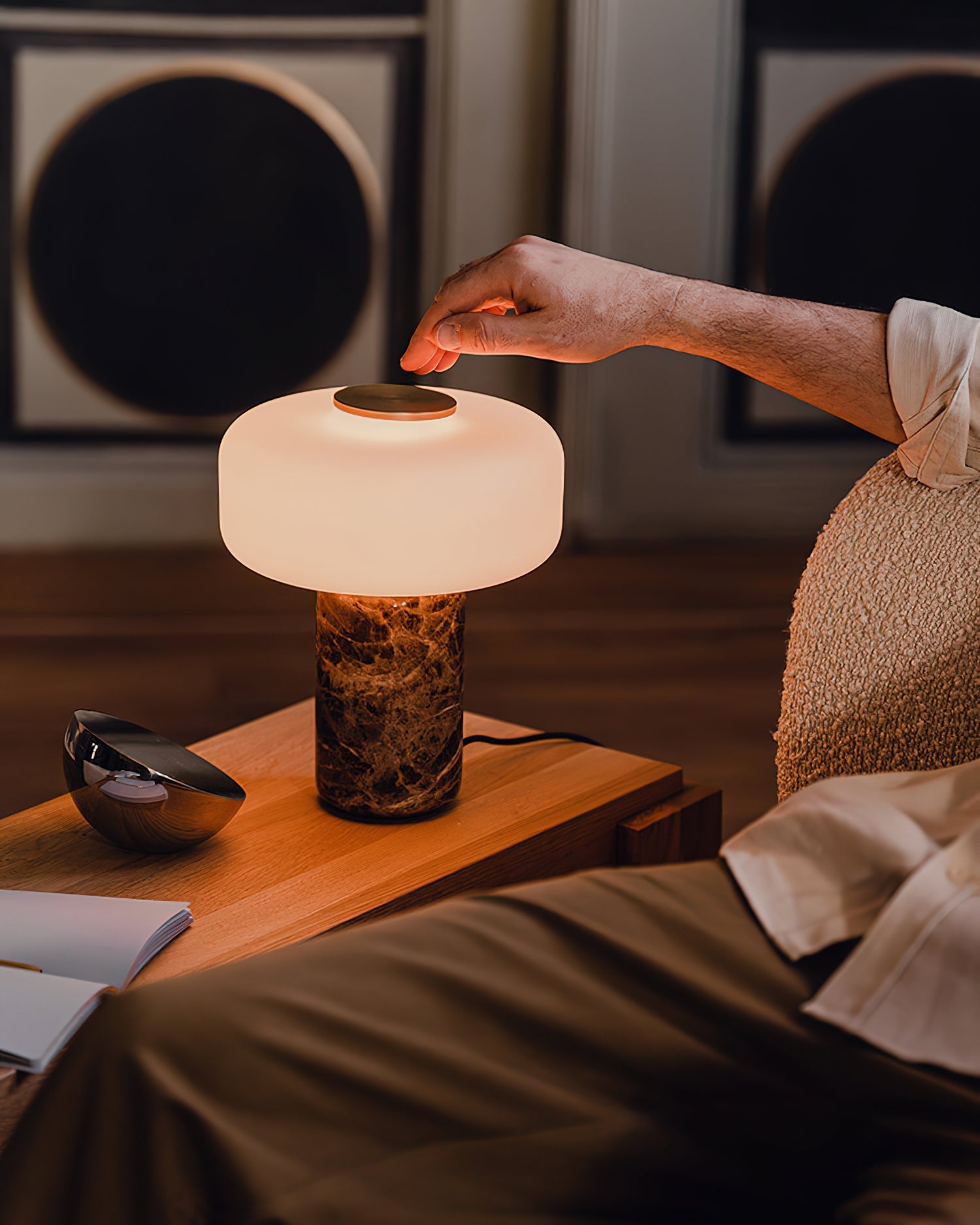 The Lennox lamp placed on a wooden side table in a modern living room setting.