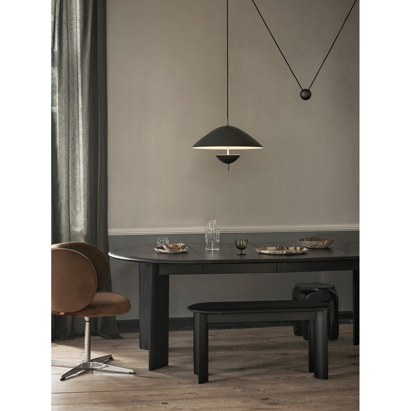 The beige Lod Pendant Lamp hanging above a minimalist dining area.