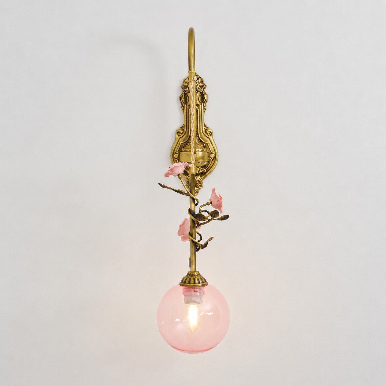 The white glass rose sconce, lit, emitting a soft, diffused light.