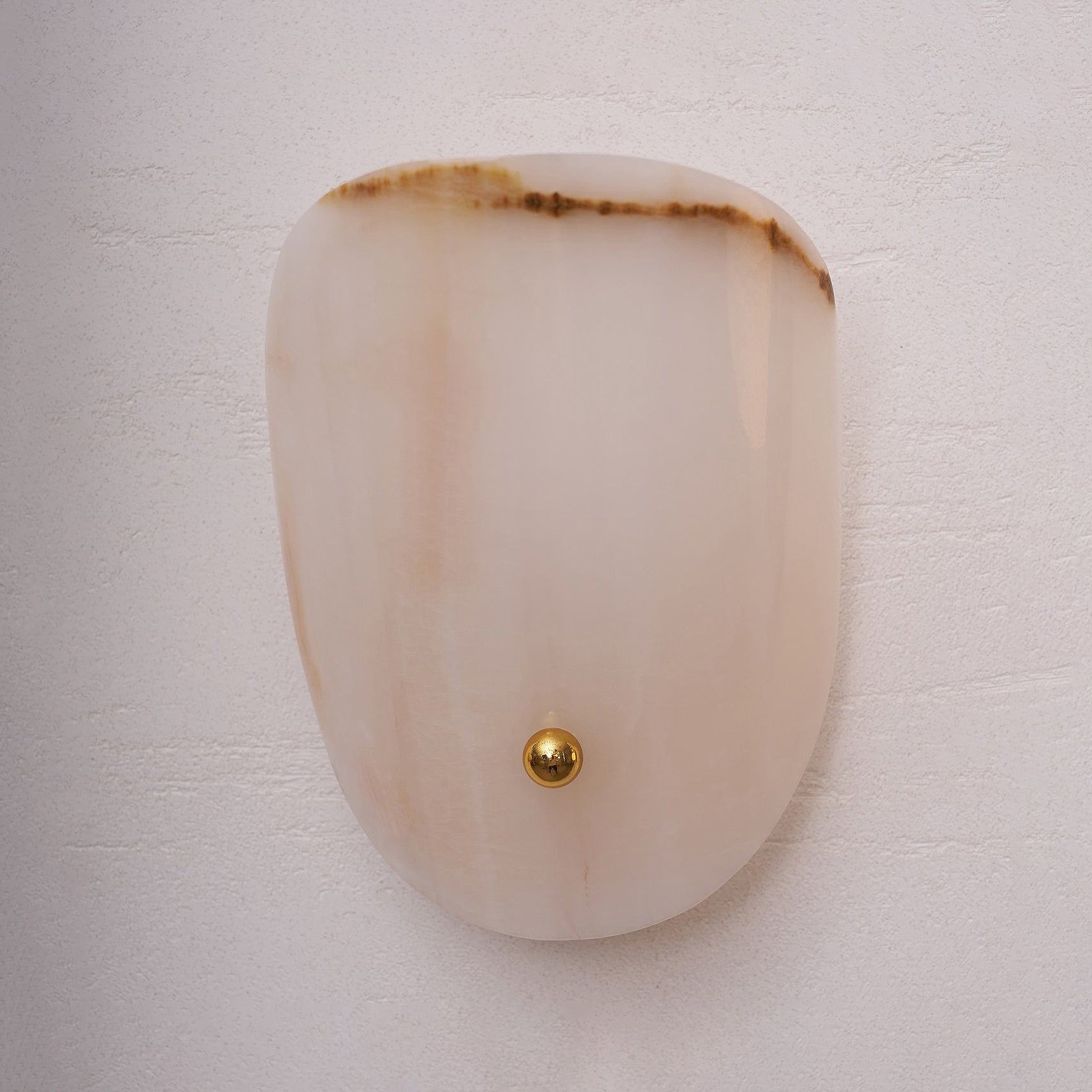 Beige onyx wall lamp highlighting its translucent layers.