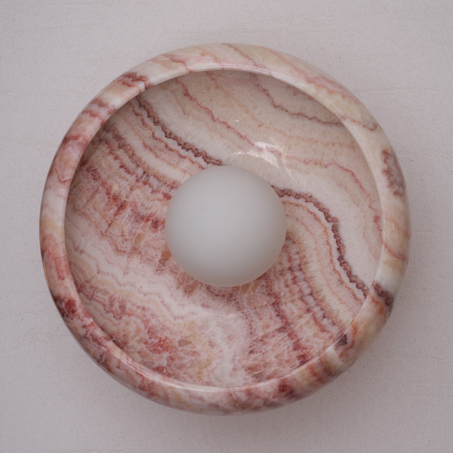 White jade wall lamp against a textured wall.