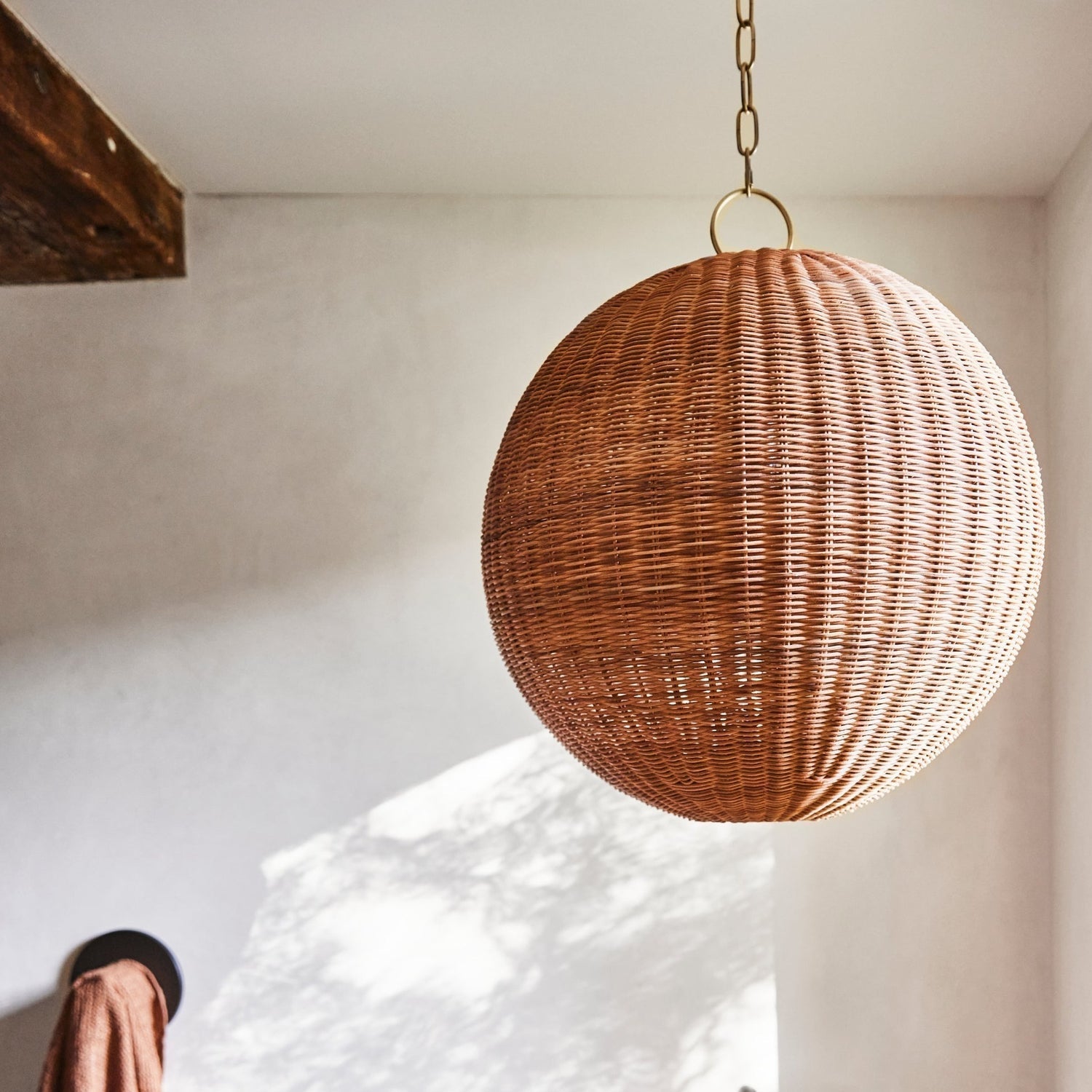 The rattan pendant lamp illuminated, casting a warm, dappled glow.