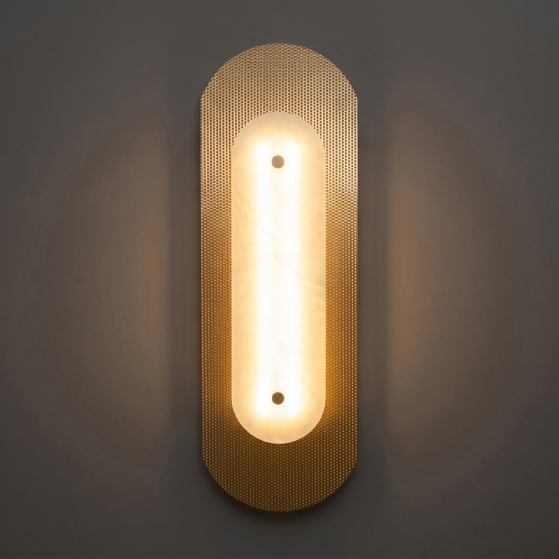 Alabaster sconce casting a warm light in a hallway.