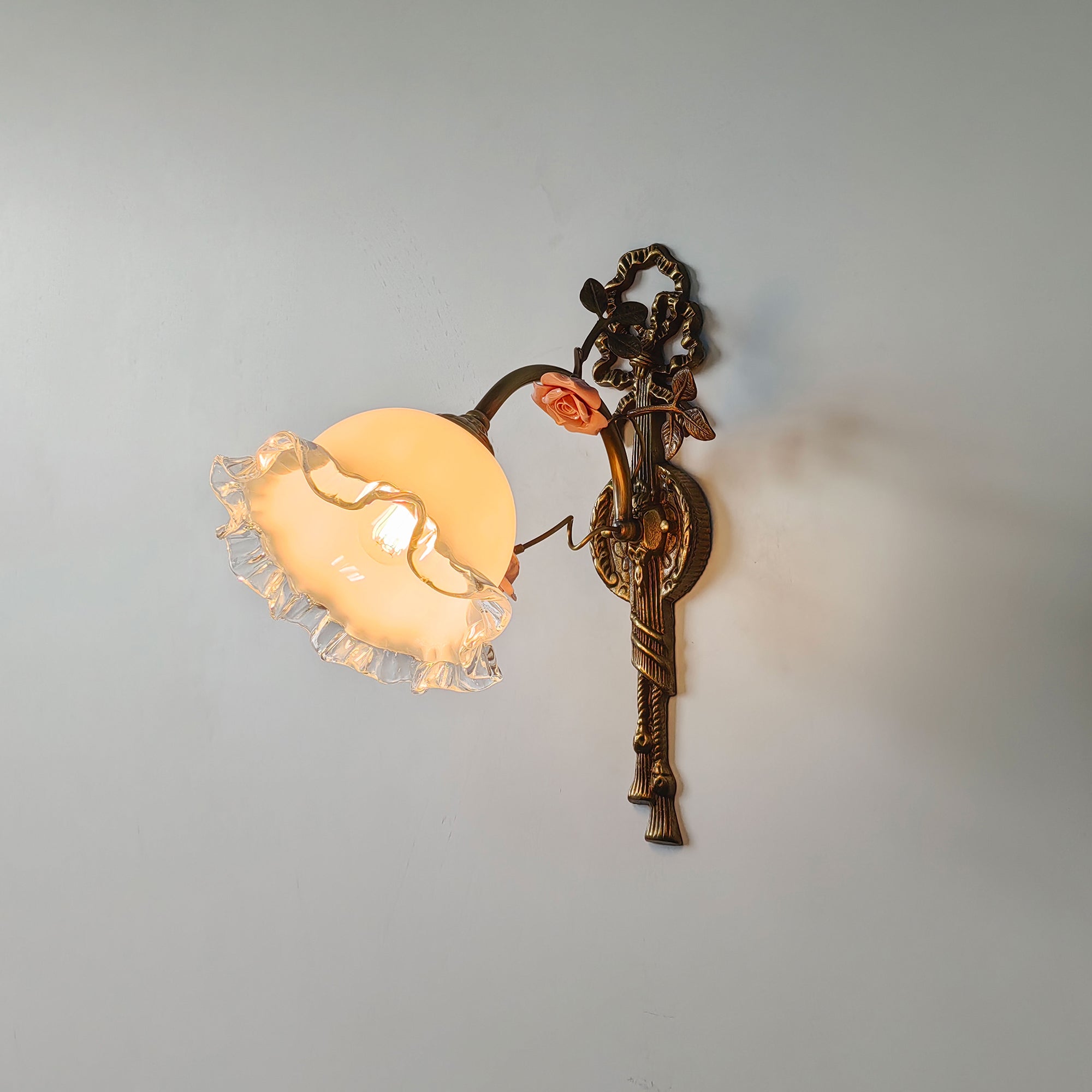 The brass and glass materials of the Neiman Wall Lamp.