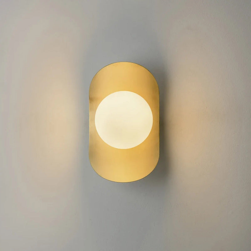 The polished brass Nouvel Wall Lamp reflecting light in a bright room.