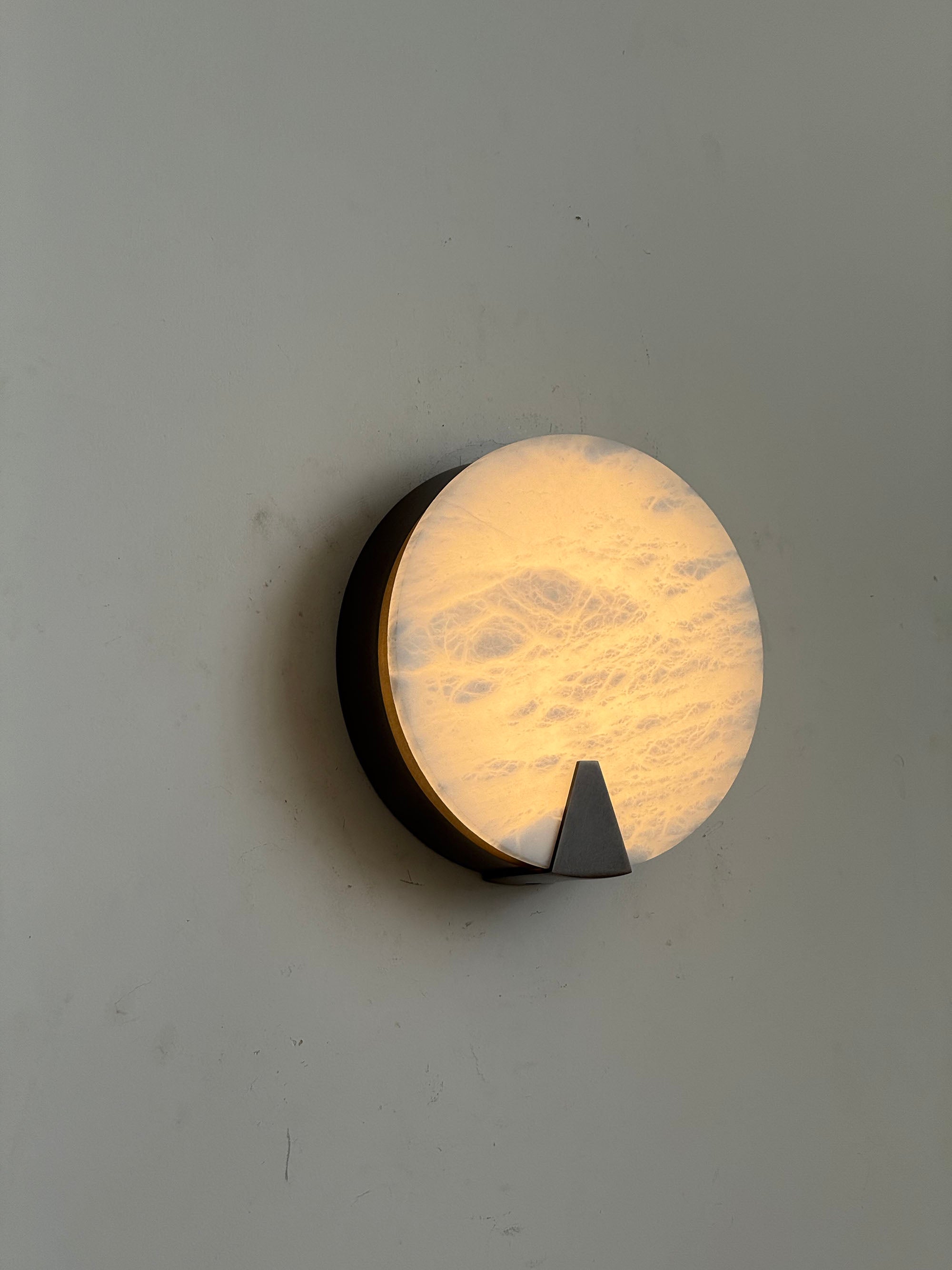 Angled view of the round alabaster sconce.