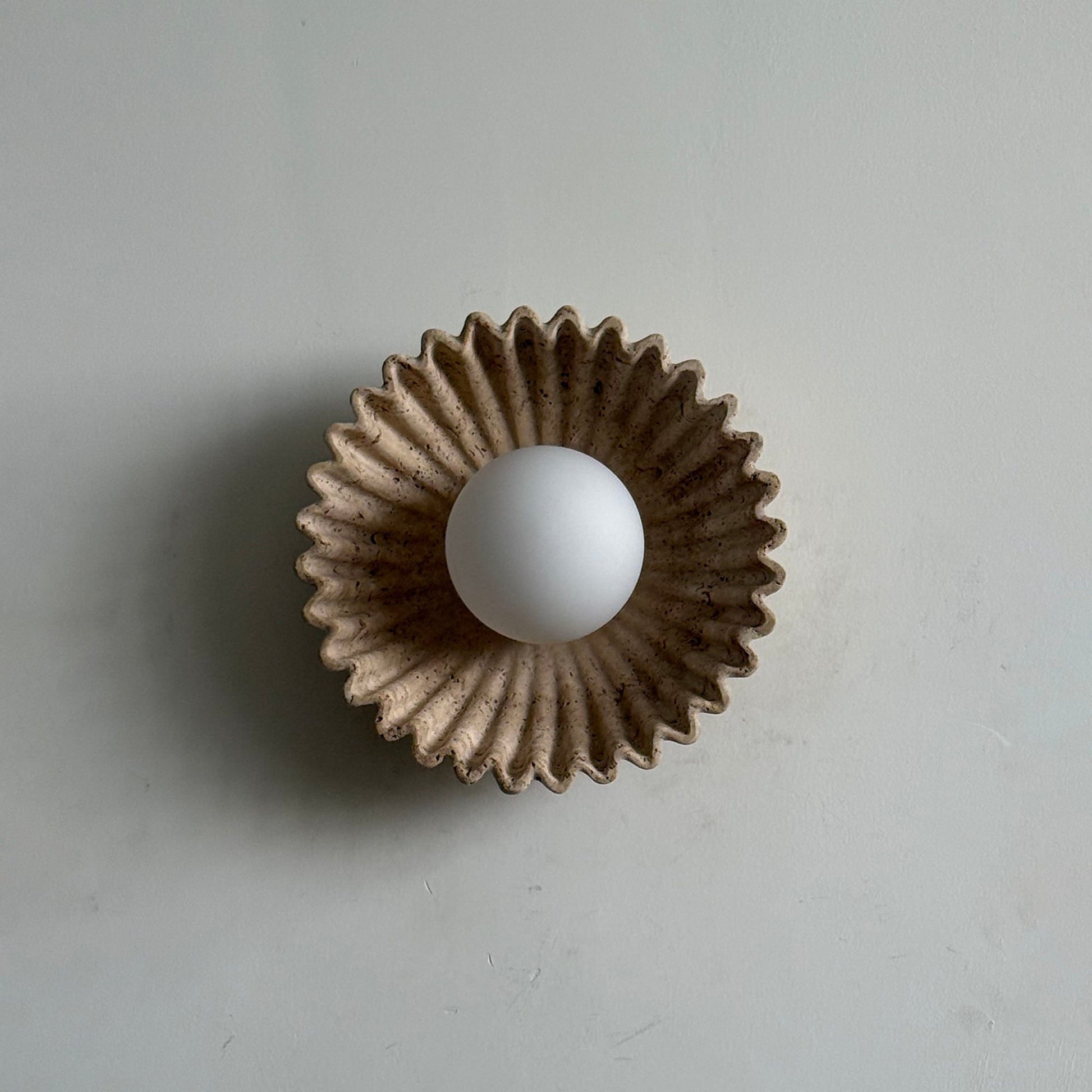 Lifestyle image showing the Ostro Sconce in a bedroom above a nightstand.