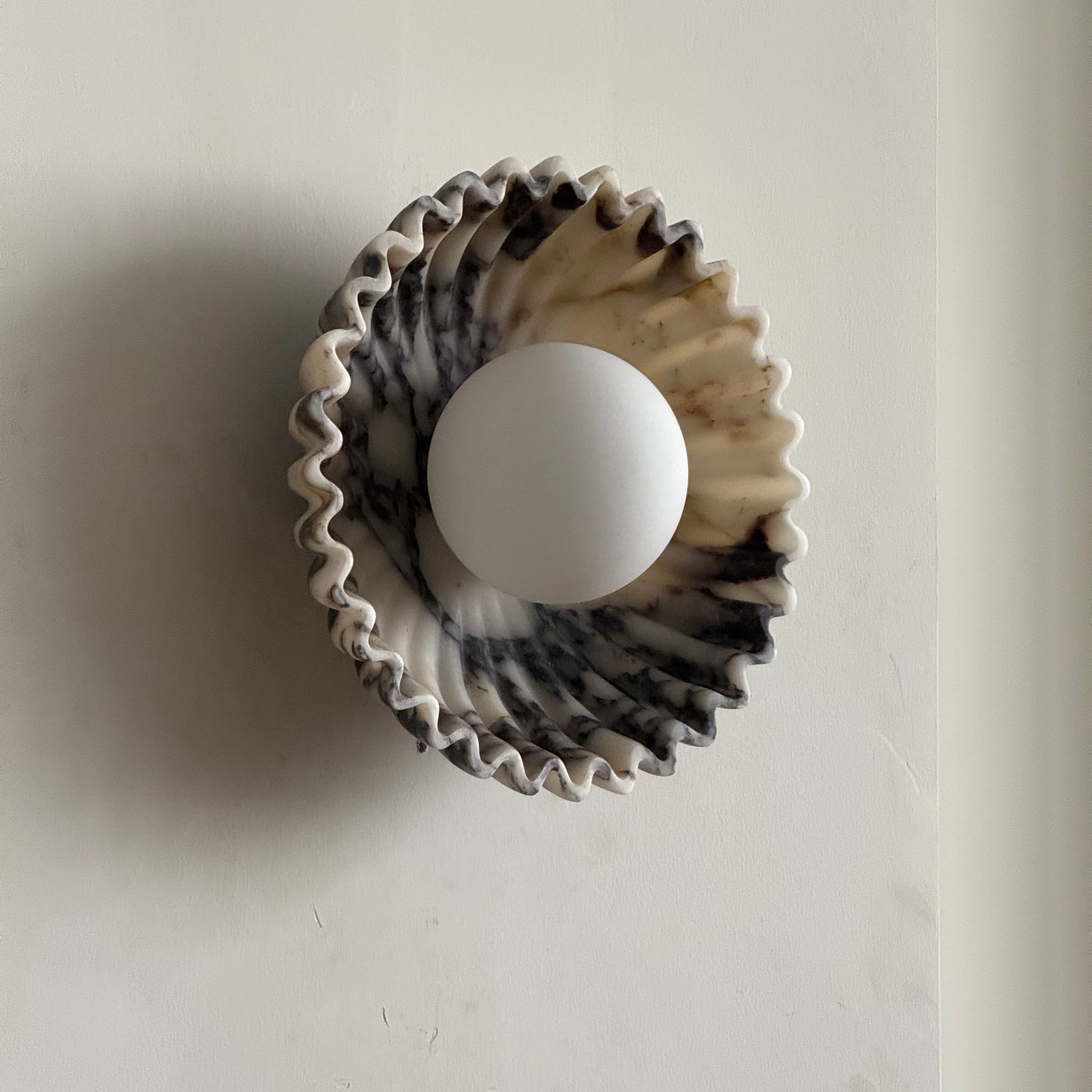 Ostro Marble Small Sconce in beige travertine, side view.