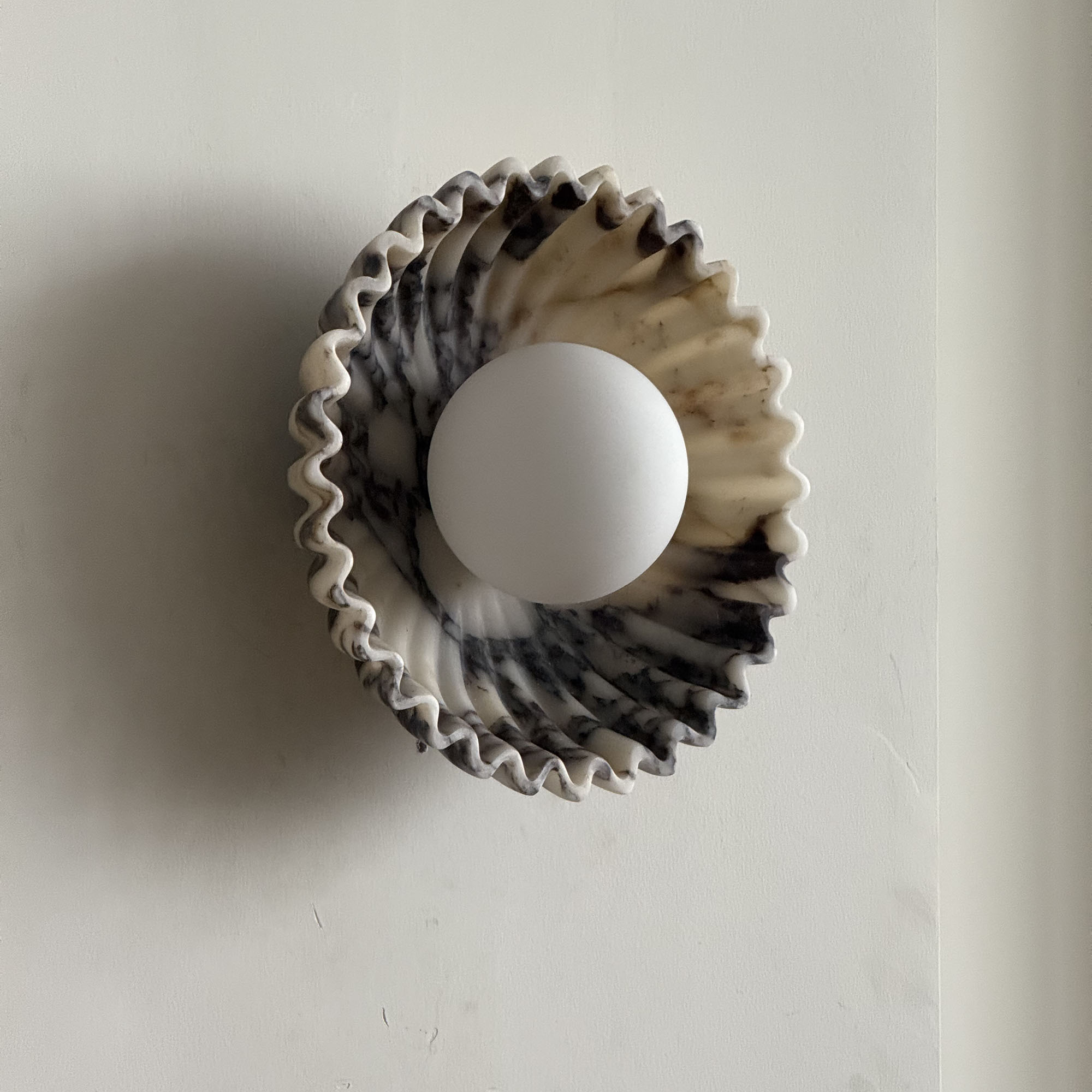 Ostro Marble Small Sconce in beige travertine, side view.