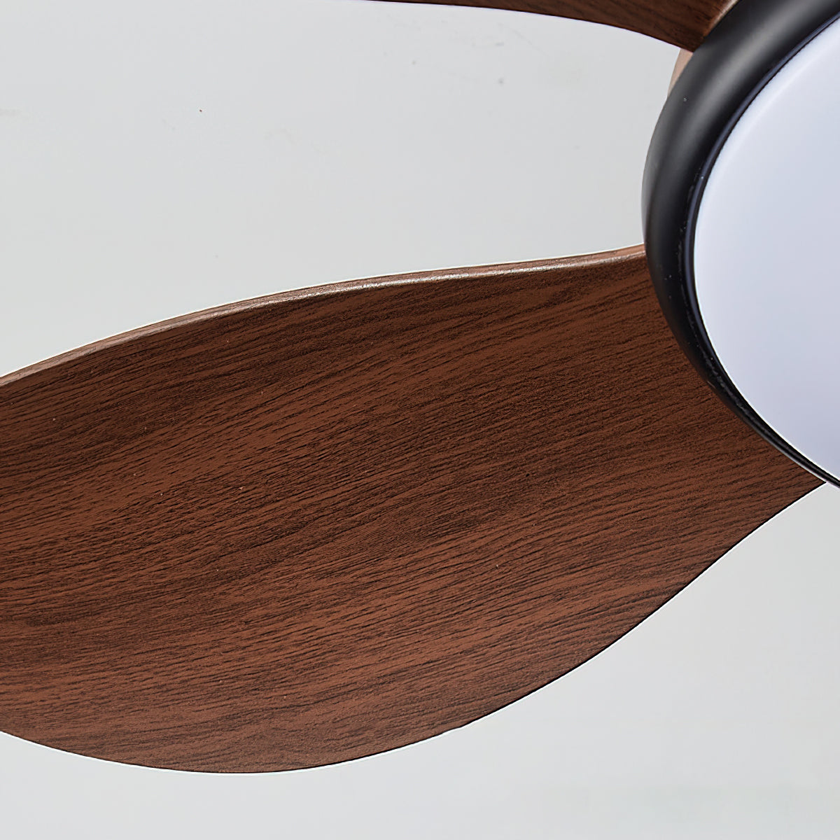 Angled view of the black Ovlaim ceiling fan against a light wall.