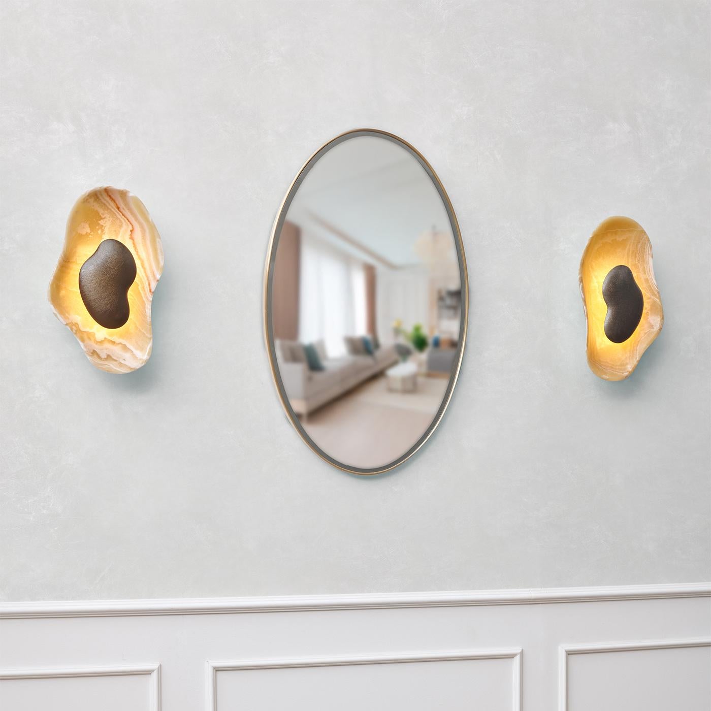 The Oyster Hammered Onyx Sconce illuminated, casting a warm glow on the wall.