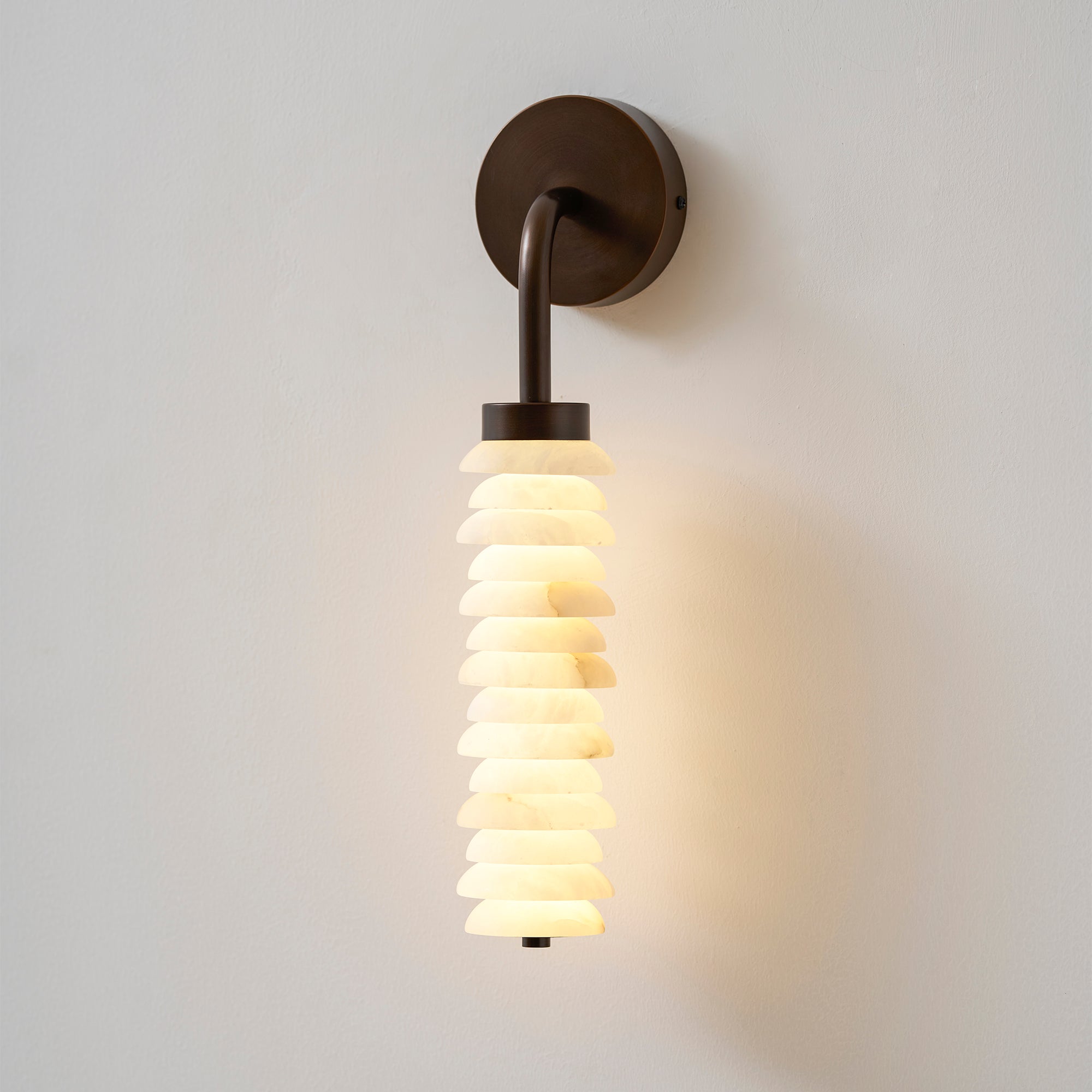 The Payson sconce casting a soft glow on a textured wall.