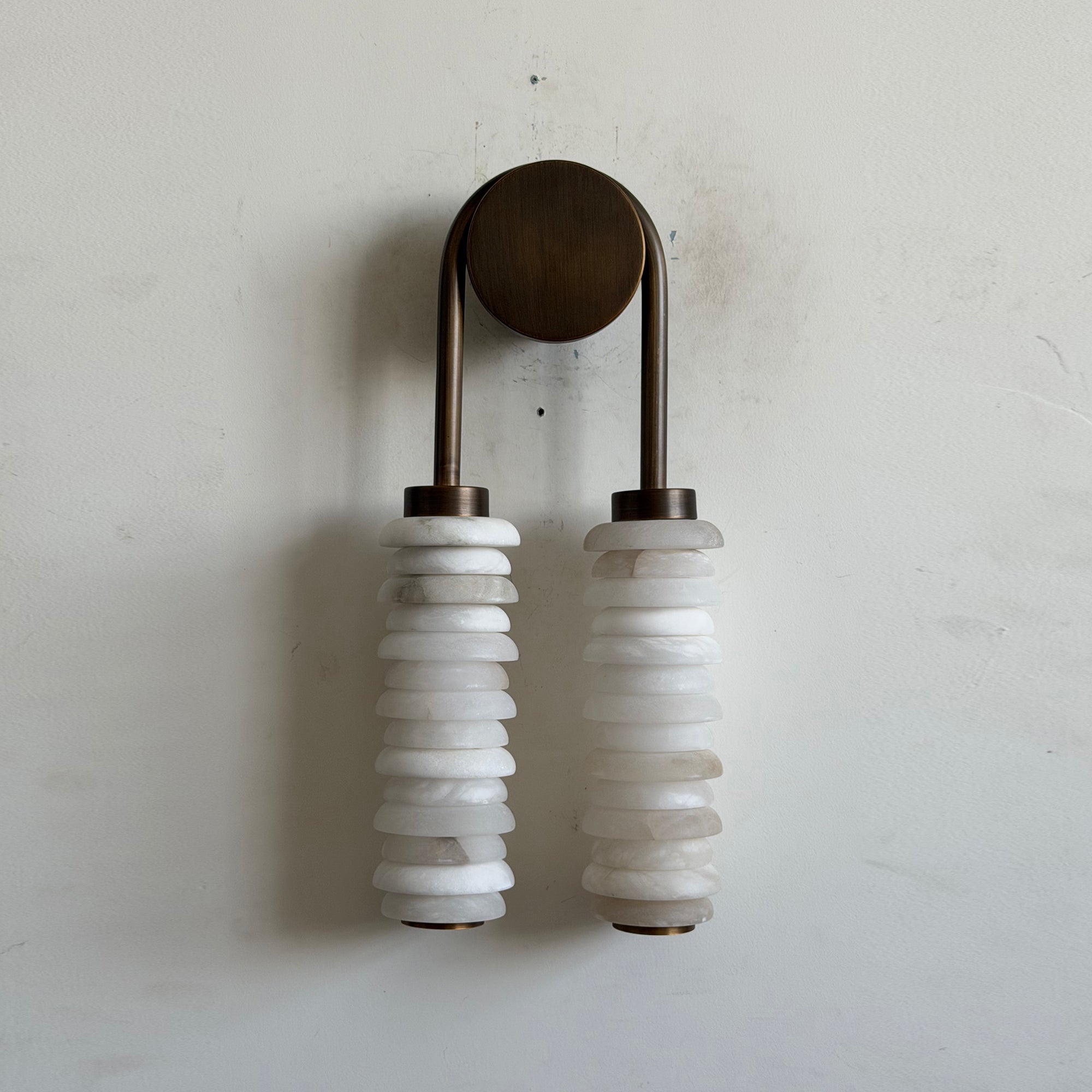 Payson Alabaster Wall Lamp against a dark colored wall.