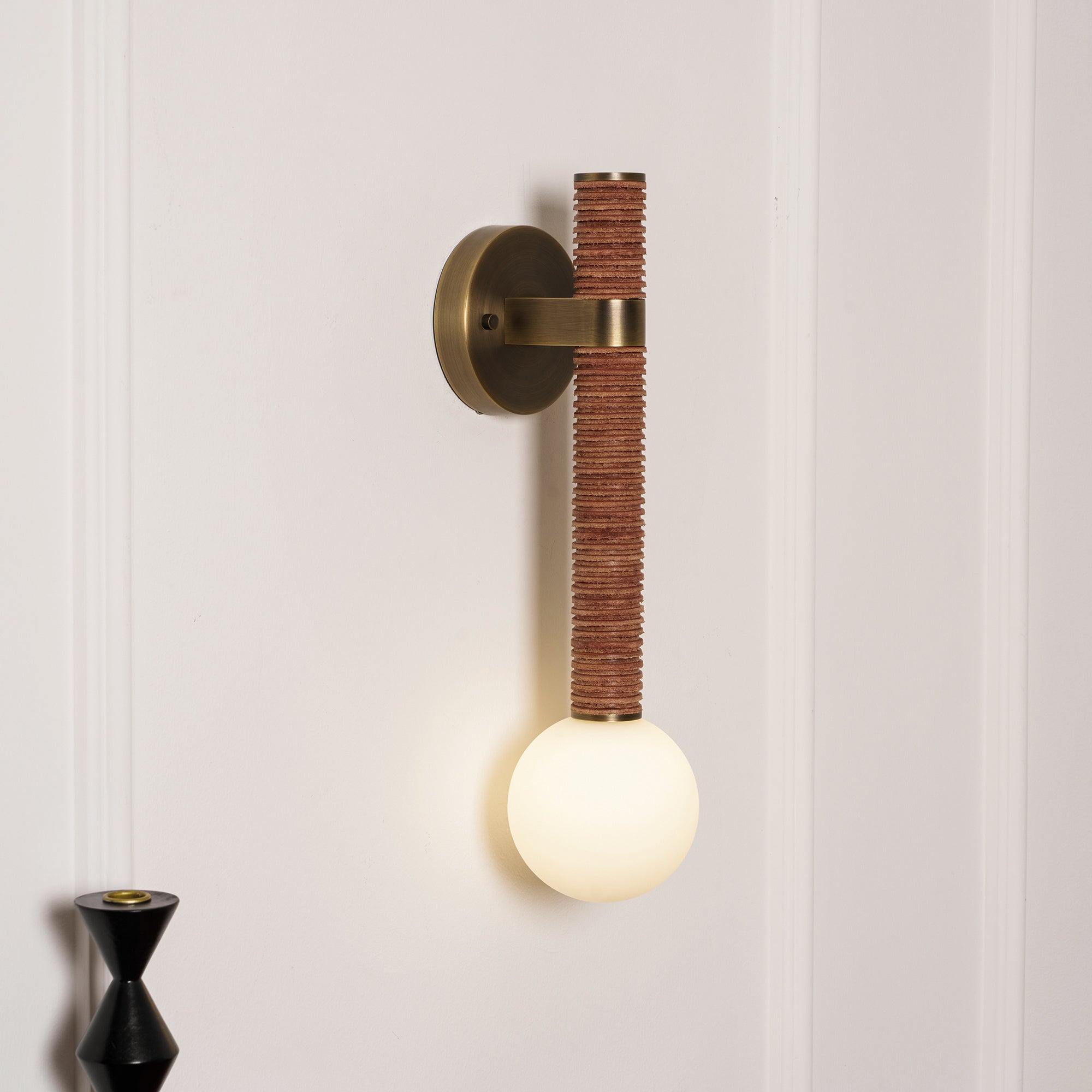 The glass globe diffuser of the Threadline sconce, showing the warm glow.