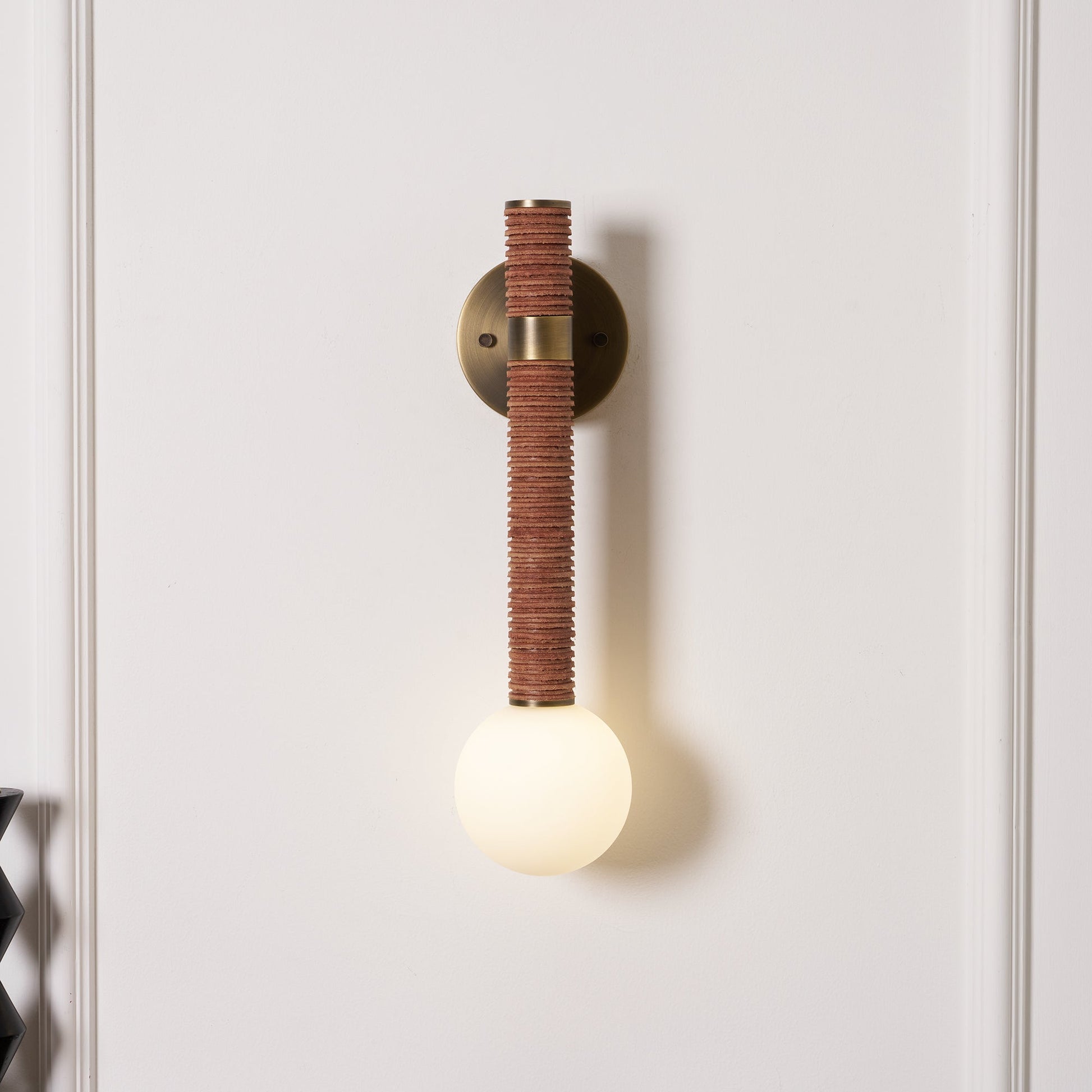 Side profile of the Threadline Globe Wall Sconce with brown leather.