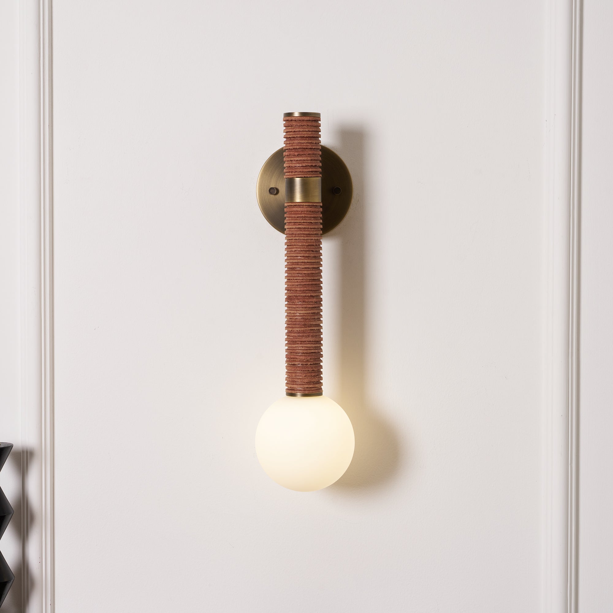 Side profile of the Threadline Globe Wall Sconce with brown leather.