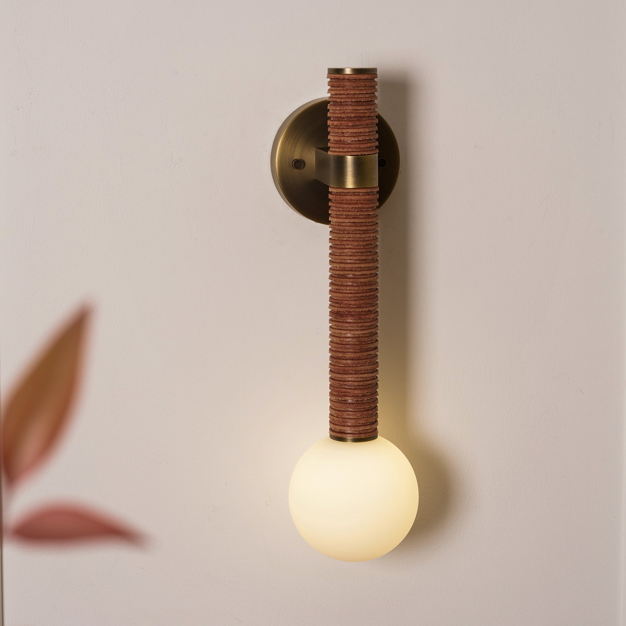 Side profile of the Threadline Globe Wall Sconce with black leather.