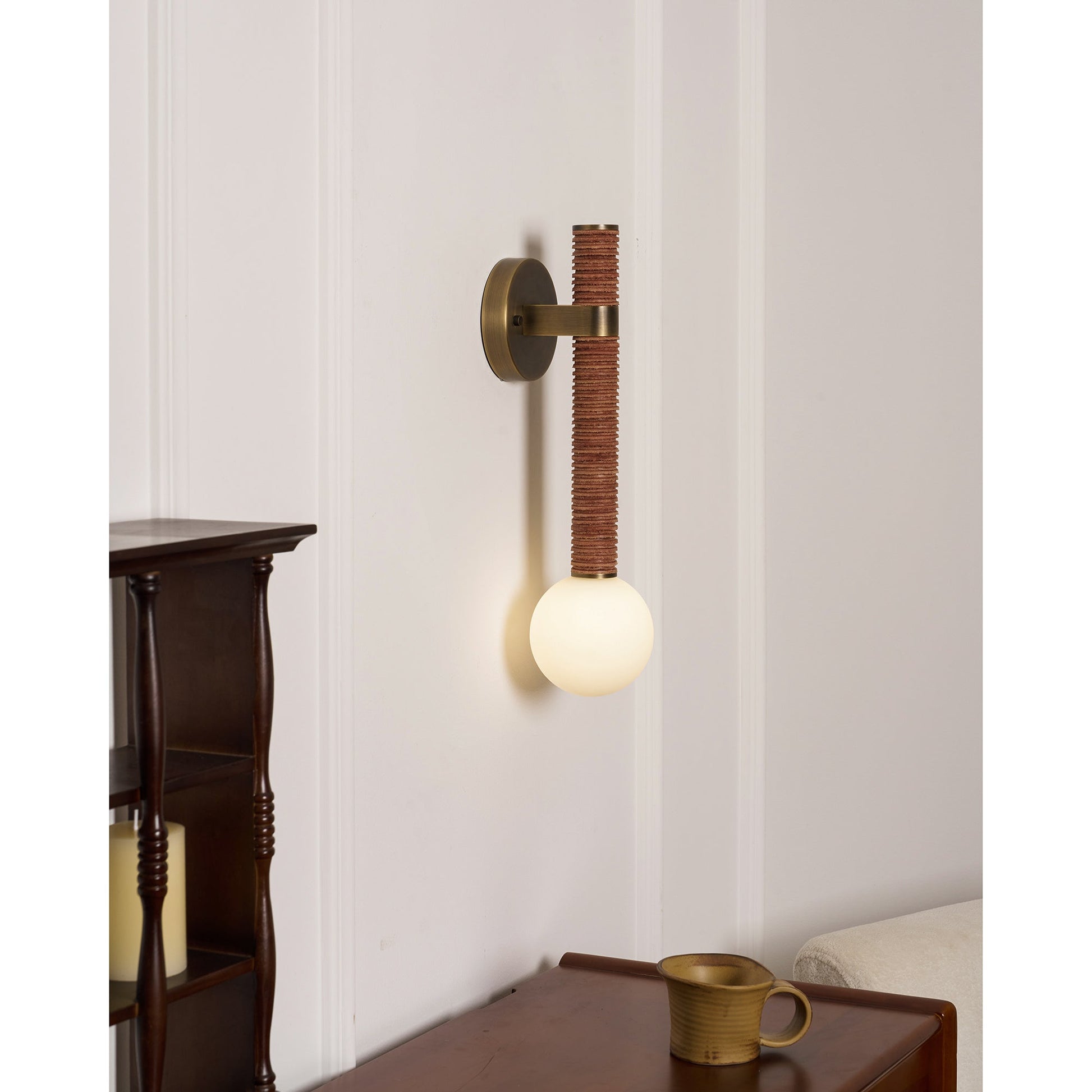 The Threadline Globe Wall Sconce shown illuminated in a modern hallway.
