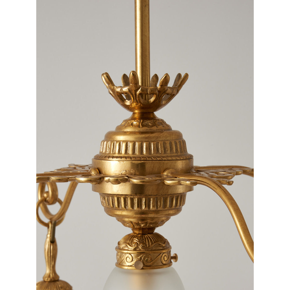 The brass and glass materials of the Quezal Chandelier in detail.