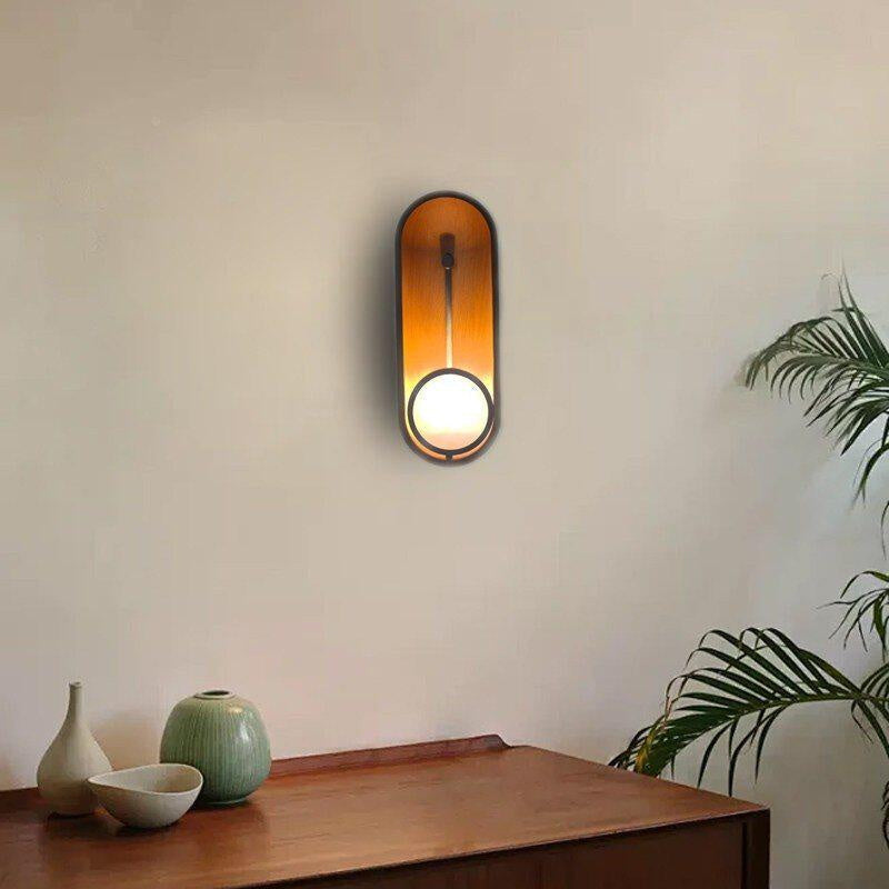 The Aperture Wall Sconce illuminated, casting a warm glow.