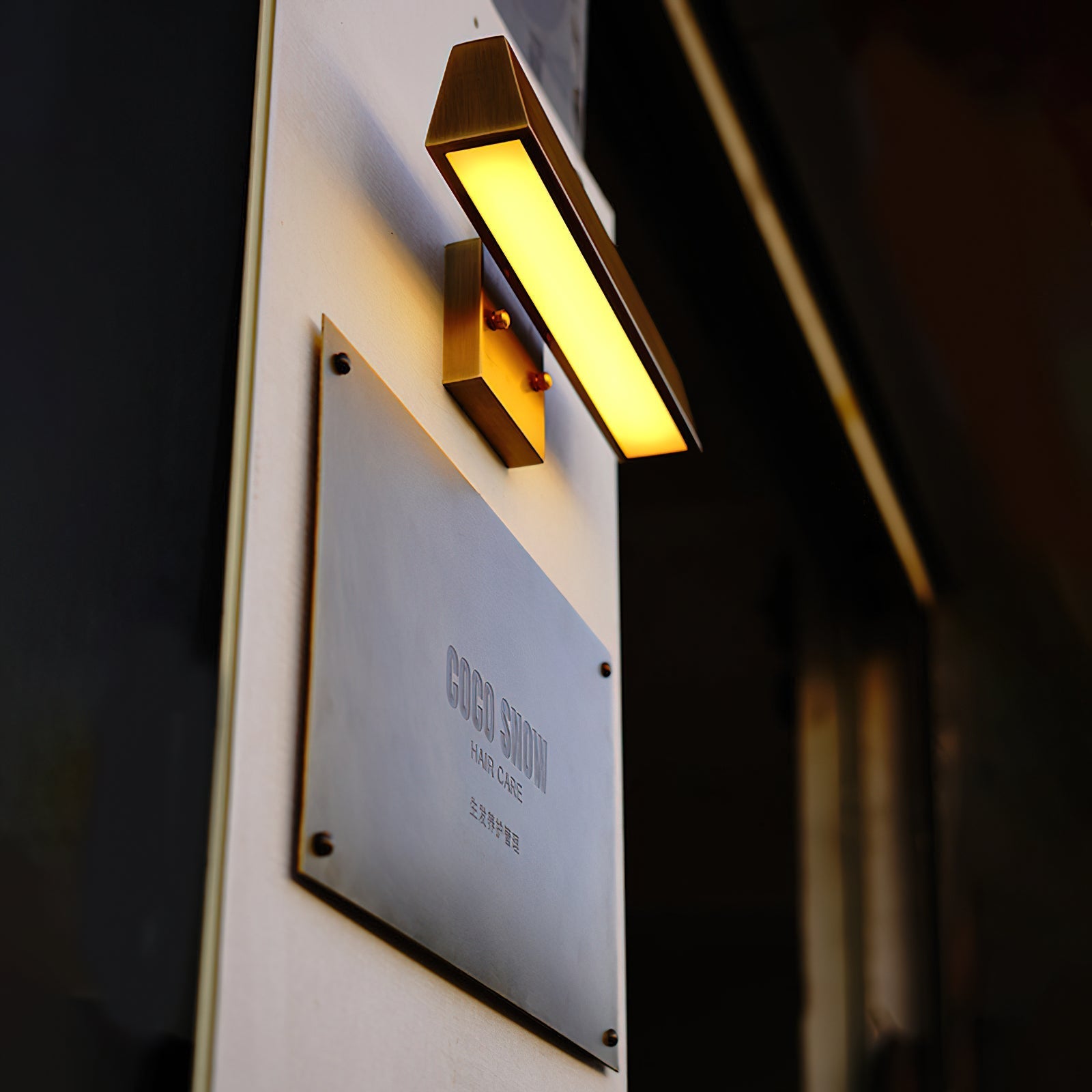 Arti Brass Wall Sconce against a light wall.
