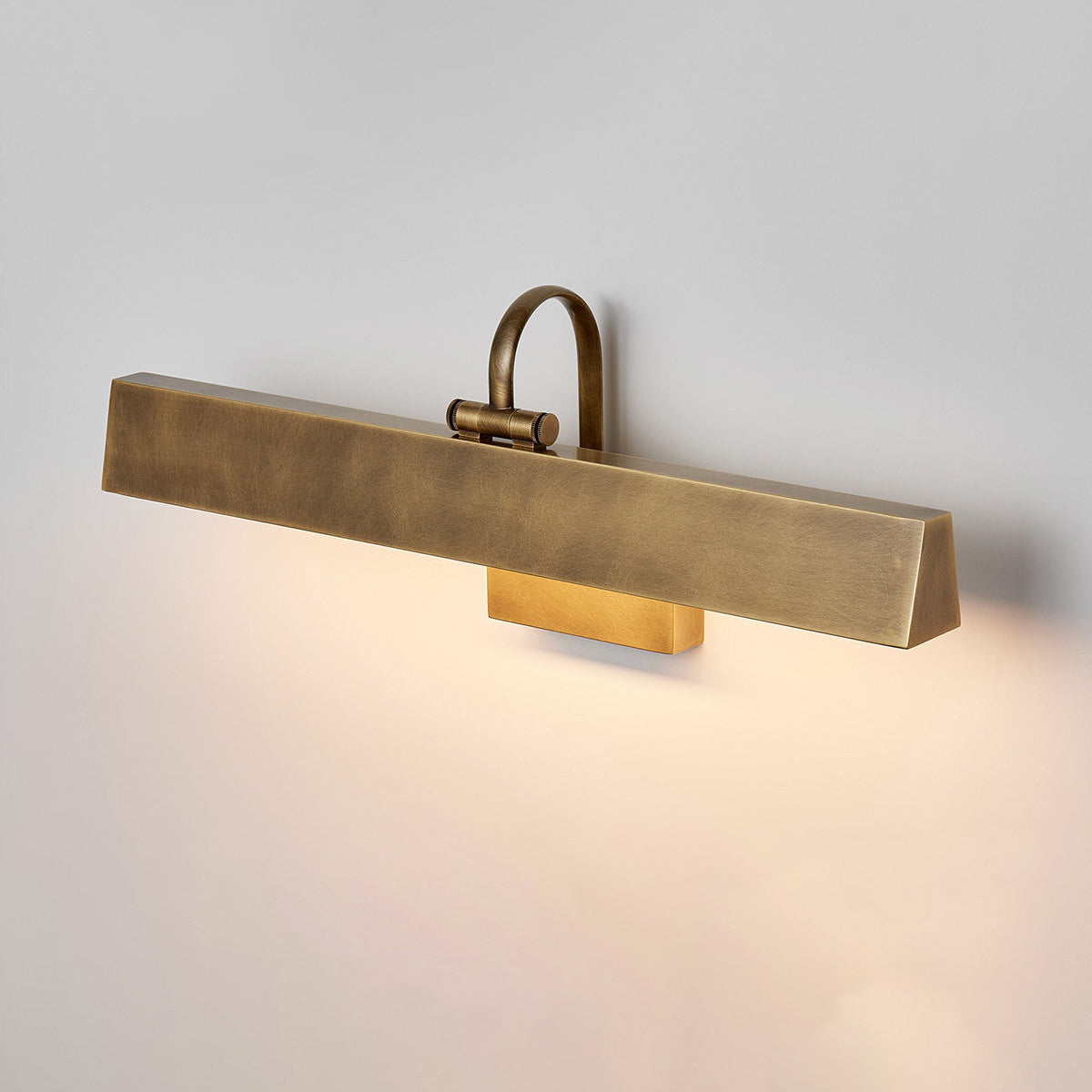 The Arti Wall Sconce illuminating a piece of art in a dimly lit room.