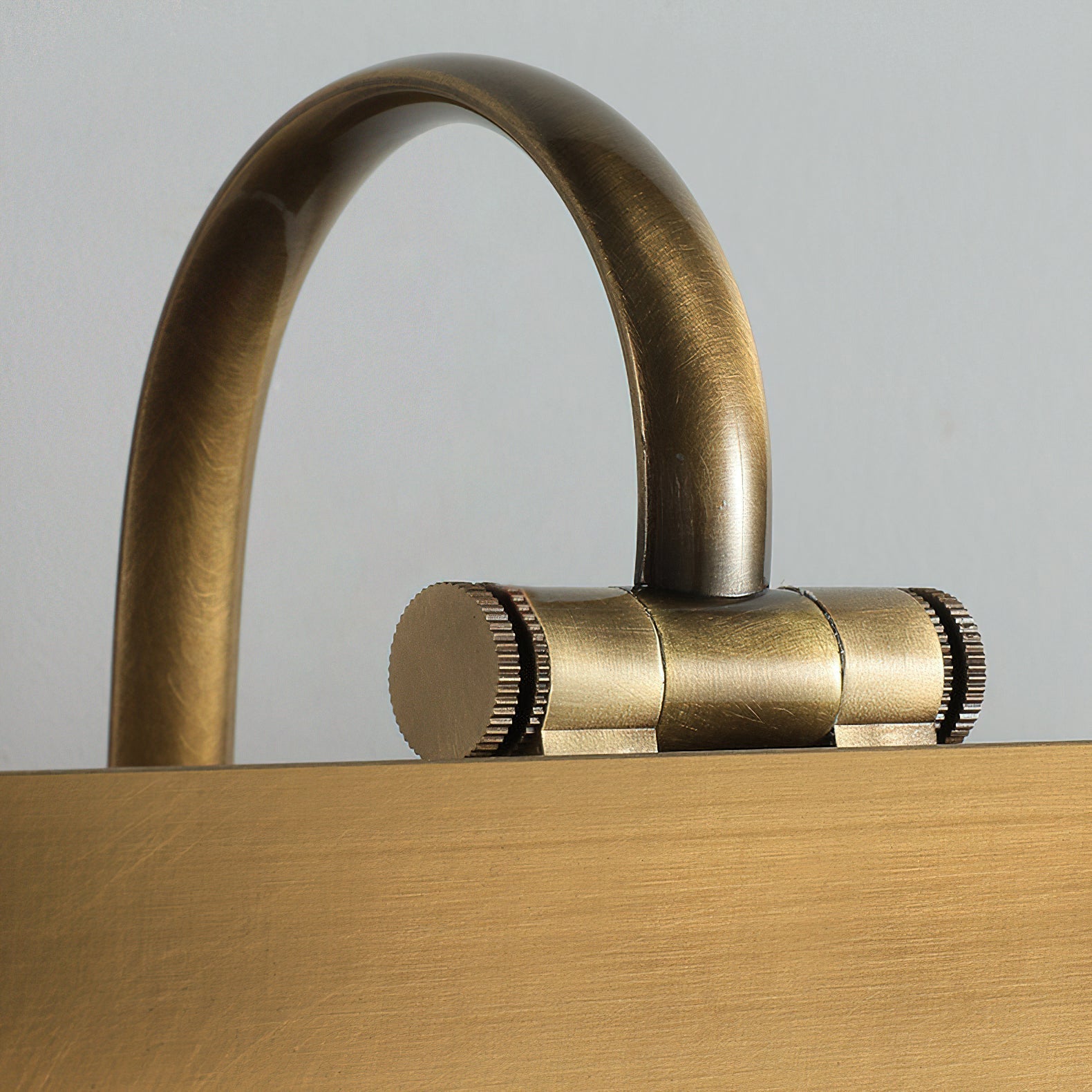 Arti Brass Wall Sconce against a light wall.