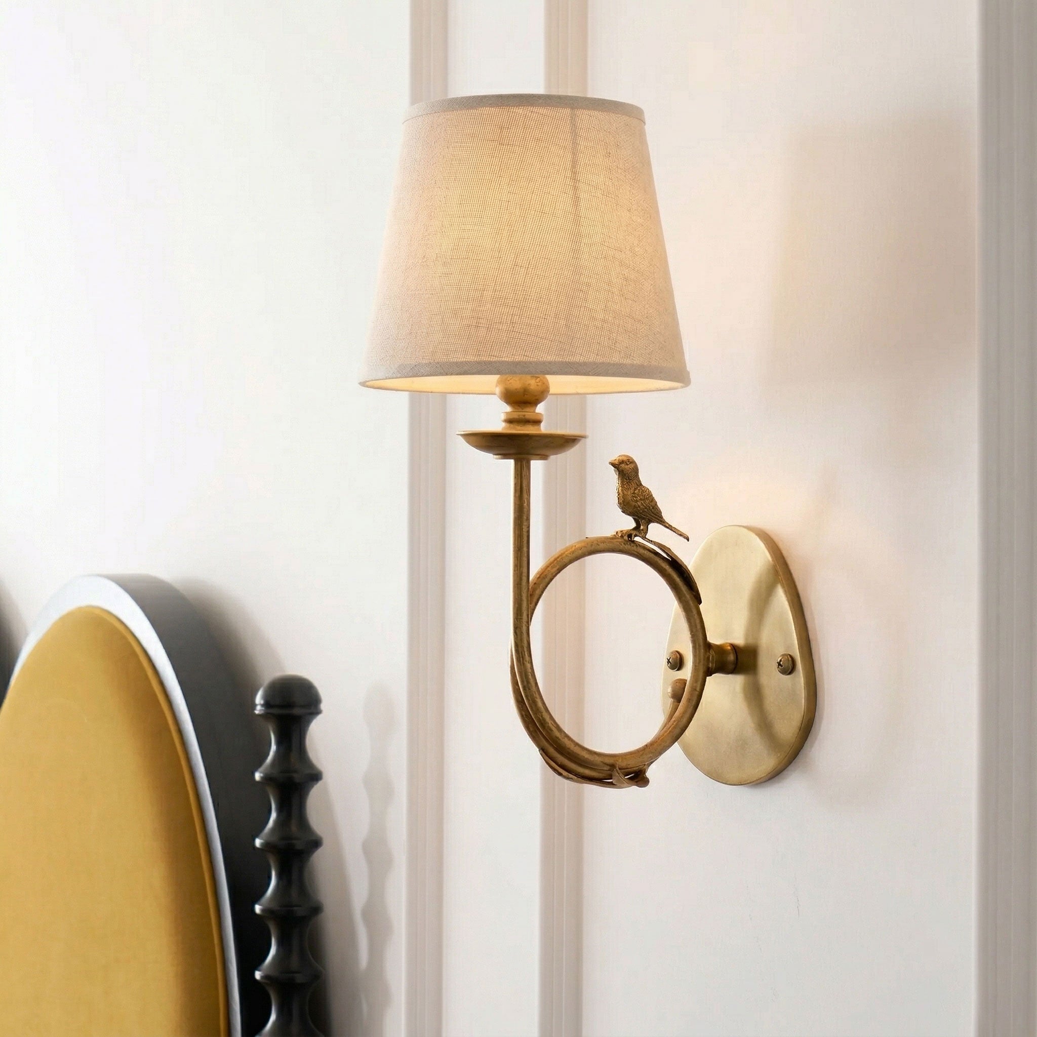 The wall sconce installed in a cozy, grandmillennial-style bedroom.