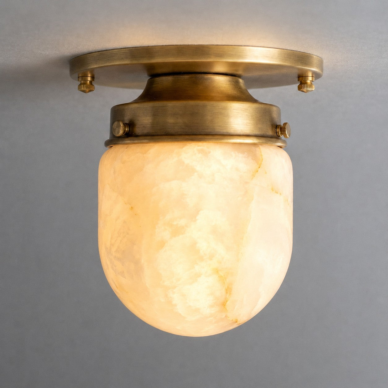 The alabaster and brass materials of the ceiling light.