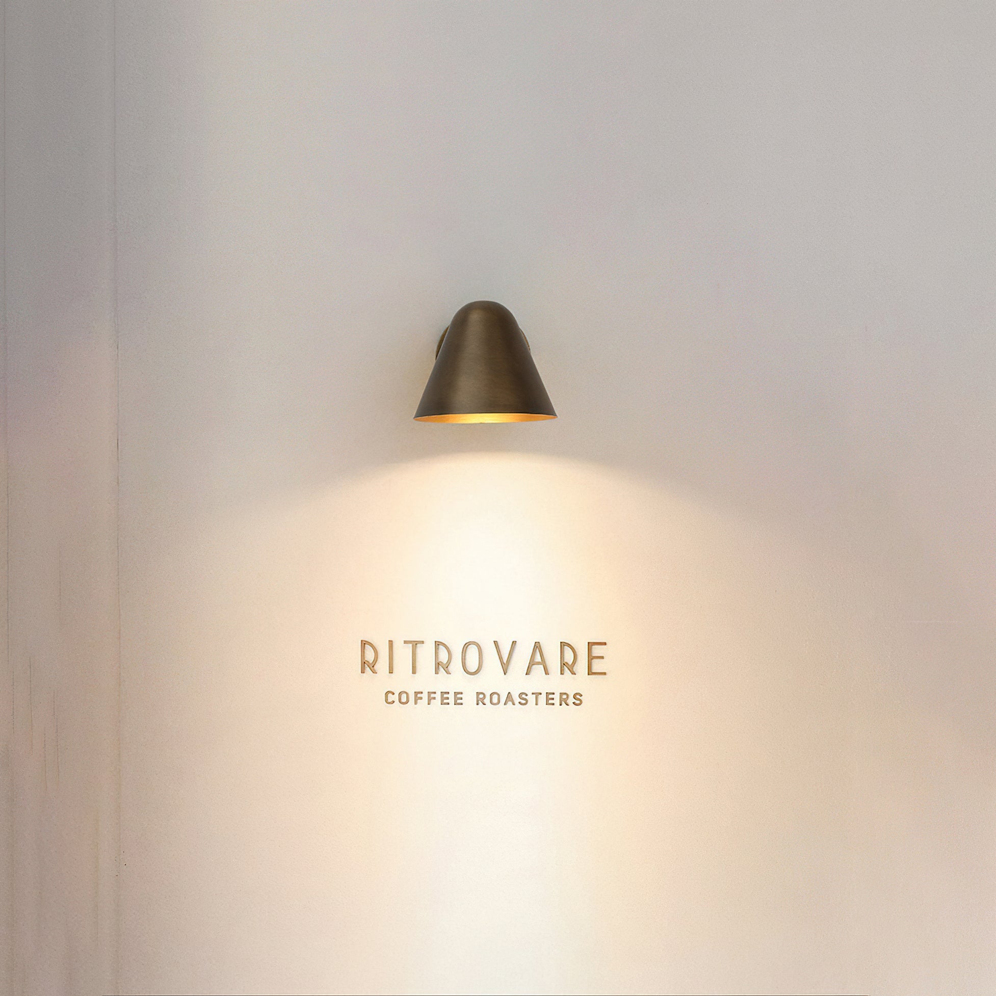 The brass finish sconce casting a warm, directional downlight.