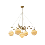 Cecil Balanced Glass Chandelier in brass finish against a neutral wall.