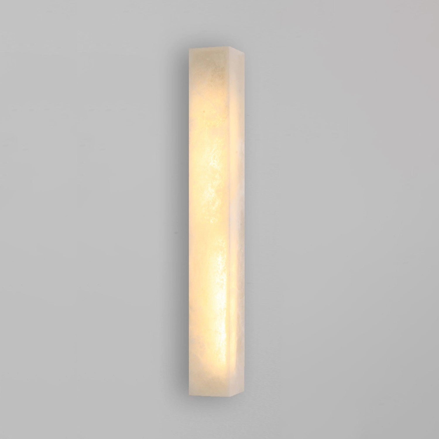Dara wall sconce casting a soft light on an art piece.