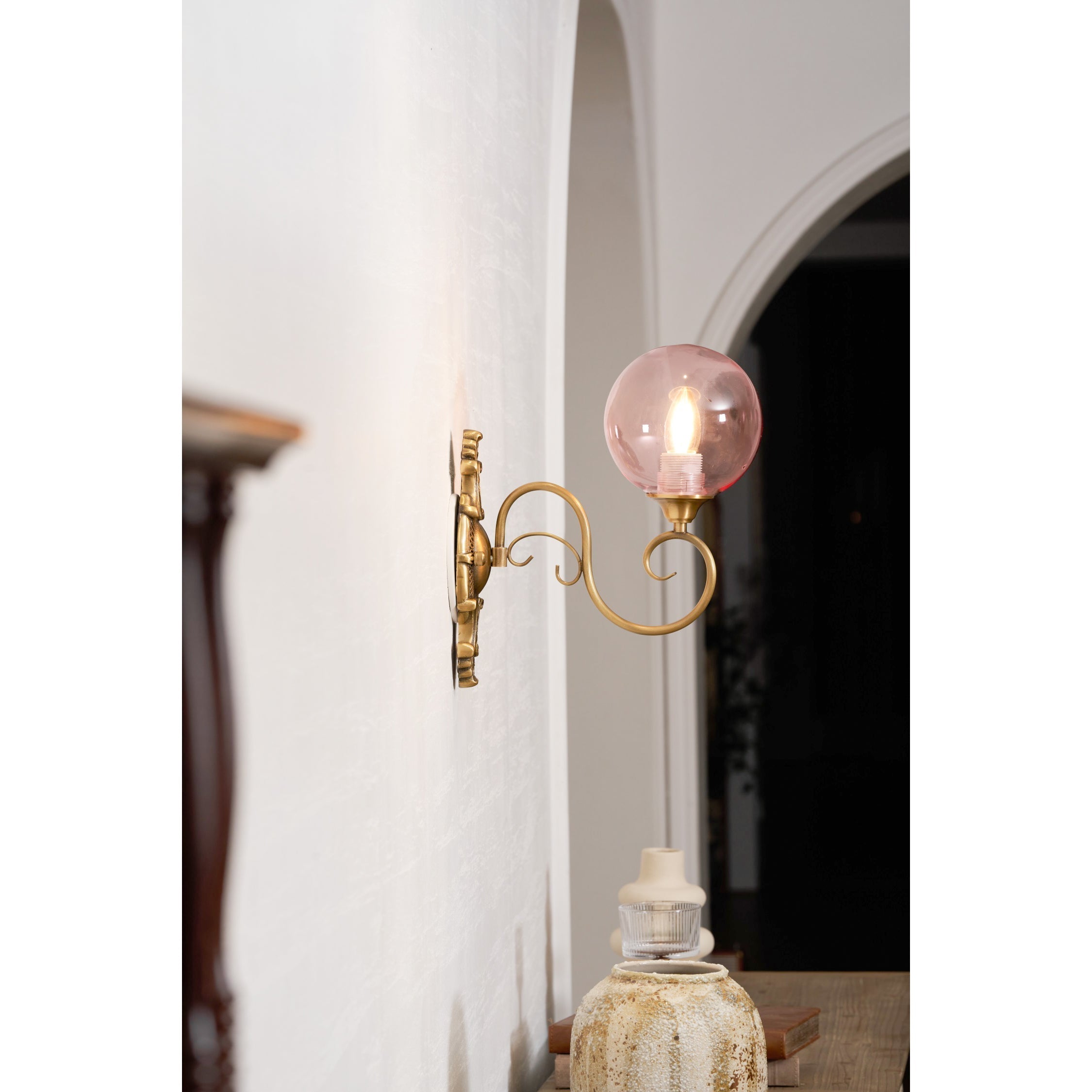 The Evelyn Wall Lamp illuminated, casting a warm glow in a room.