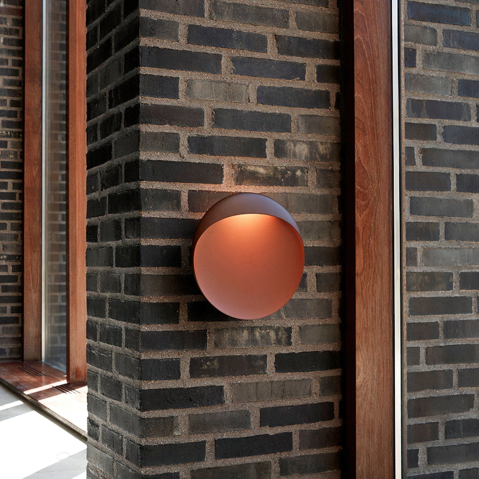 Flindt Round Wall Sconce in black, against a light wall.