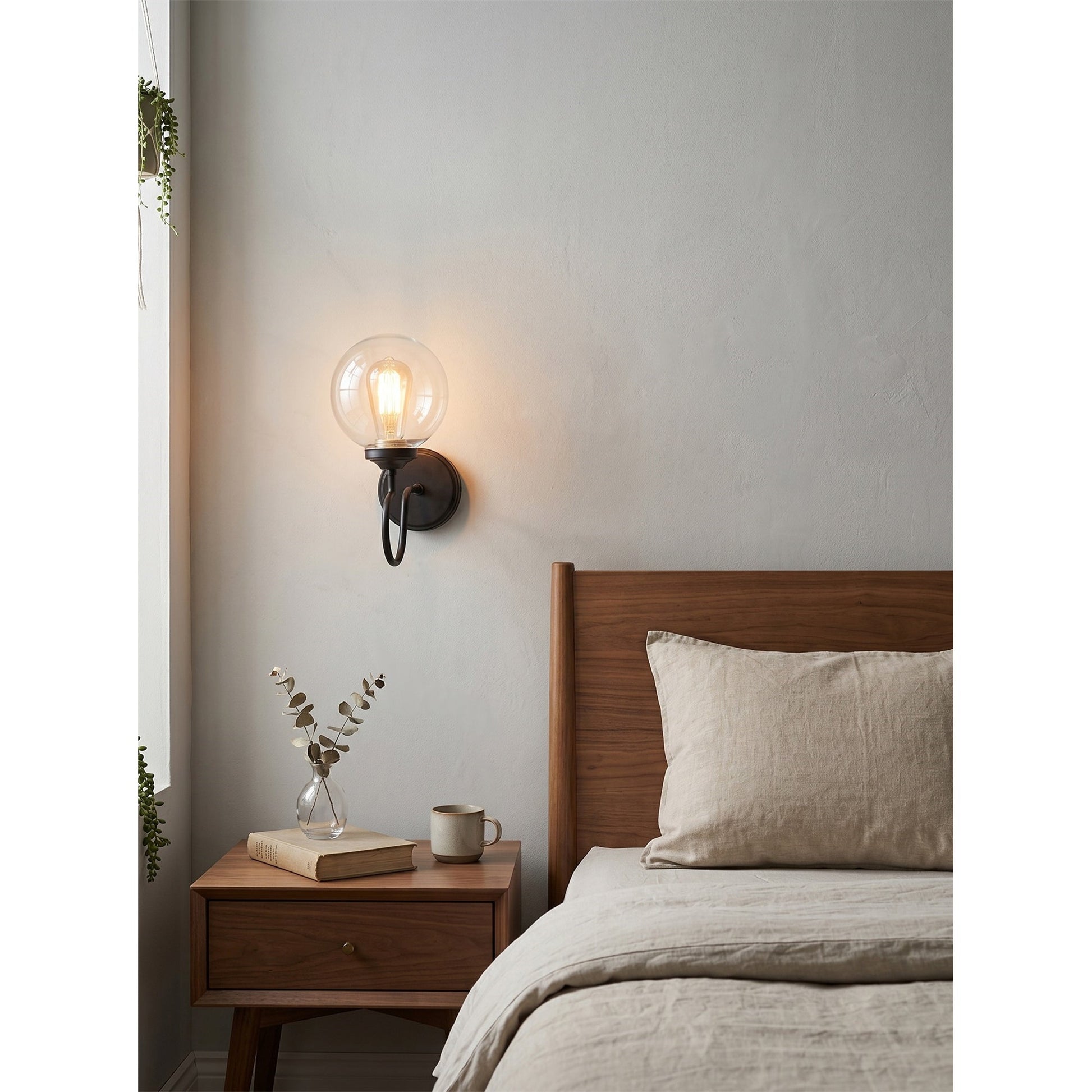 The Floren Wall Sconce in brass, providing ambient light in a bedroom.