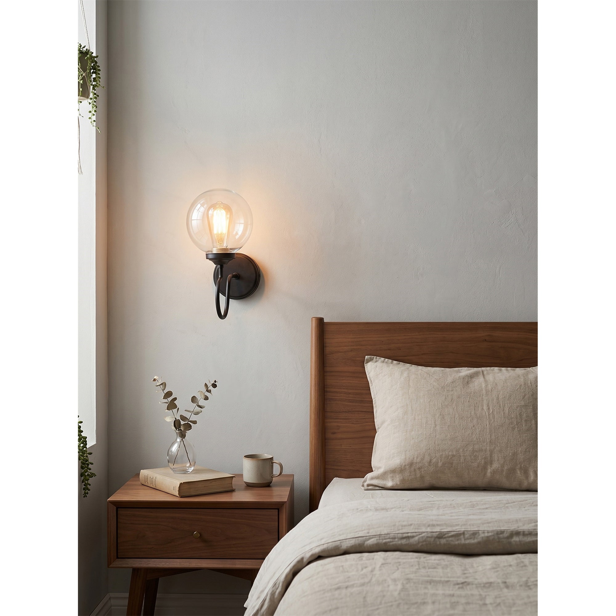 The Floren Wall Sconce in brass, providing ambient light in a bedroom.