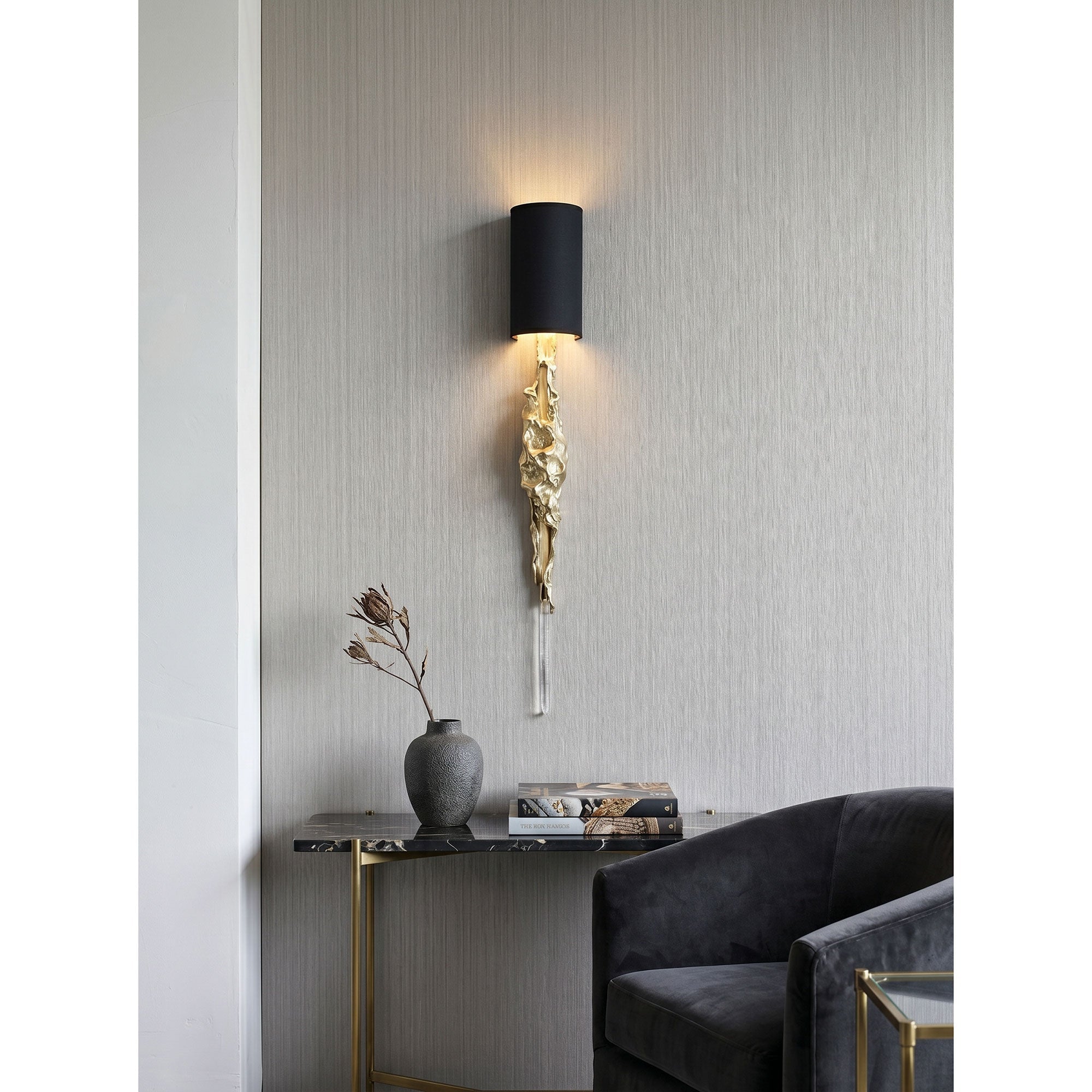 The interplay of light between the warm brass, cool crystal, and dark fabric shade.