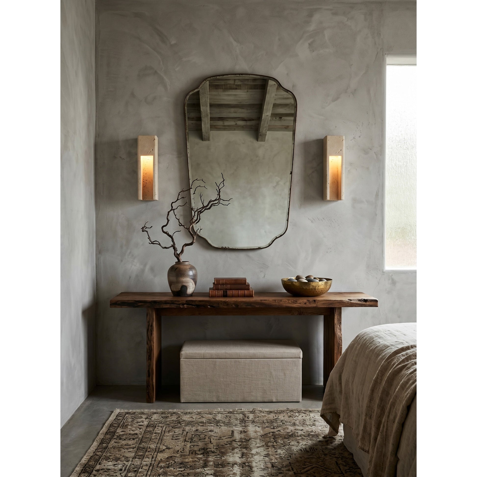 Silver gray Graziano Wall Sconce shown illuminated against a dark wall.