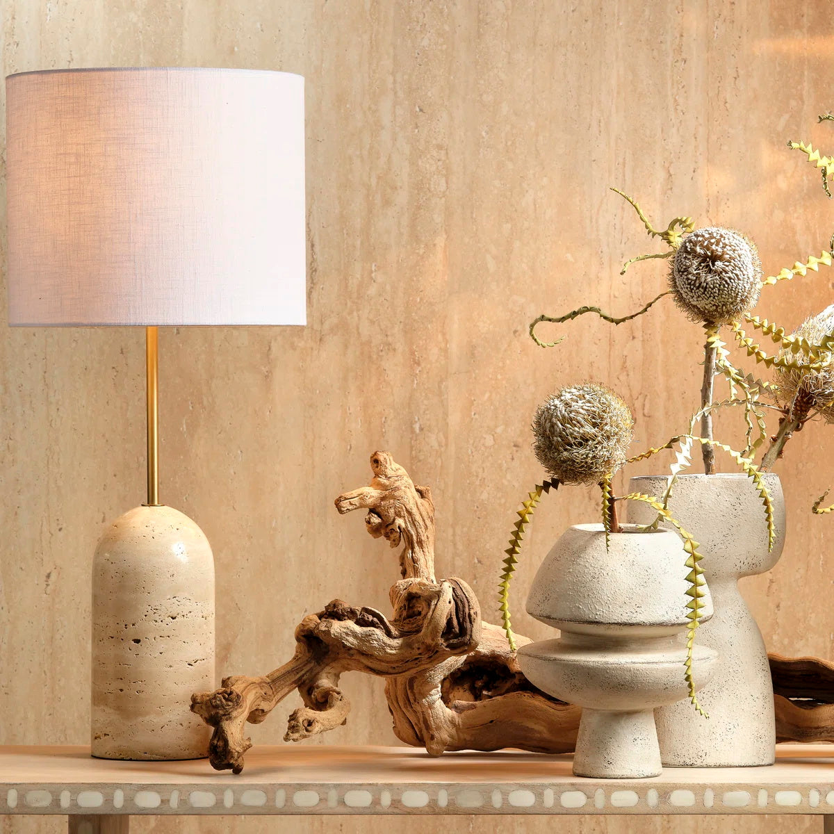 The brushed brass neck connecting the stone base and the lampshade.