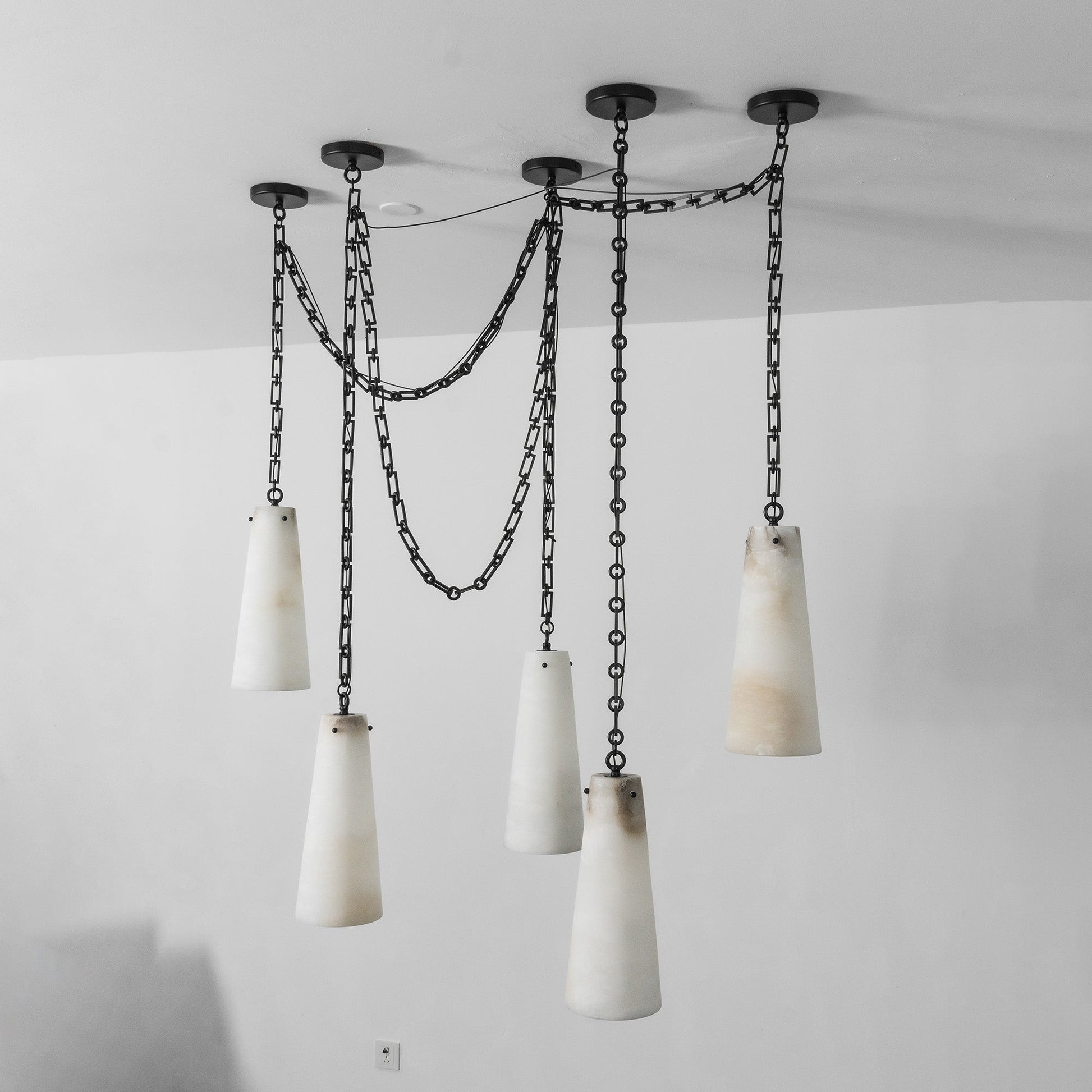 The industrial chandelier against a light wall.