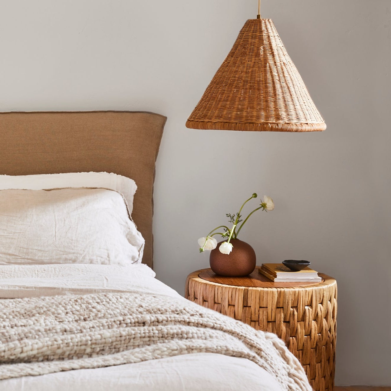 The rattan pendant lamp casting a warm, diffused glow.