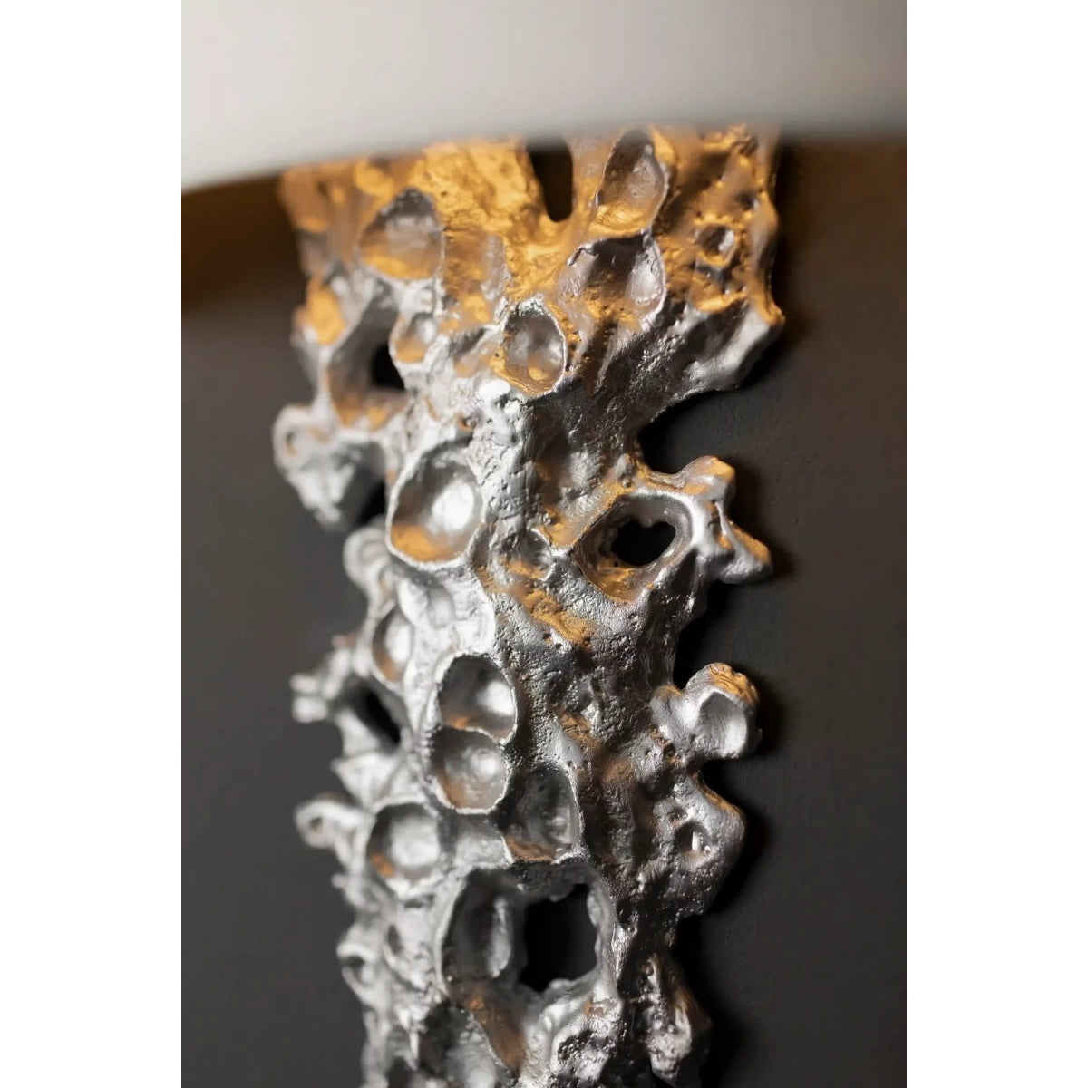The brass finish Lava sconce against a textured concrete wall.