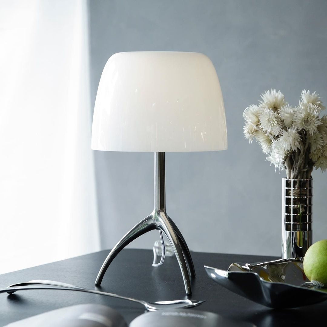 Detail shot of the sleek chrome tripod base of the Lumiere Table Lamp.