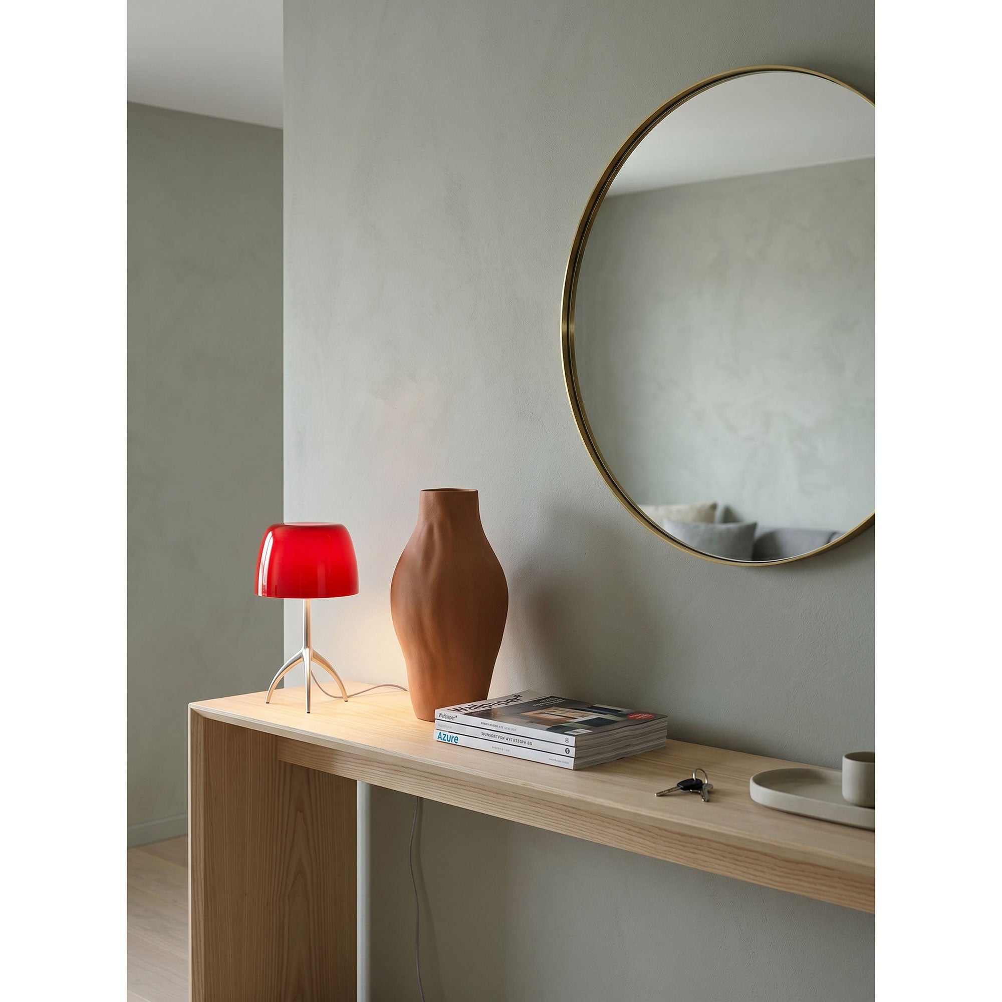 The Lumiere Table Lamp with a red shade adding a pop of color to a neutral room.