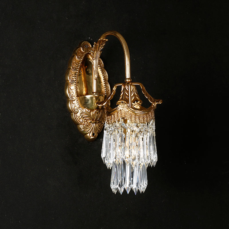The brass and crystal sconce shown against a dark, moody wall for contrast.