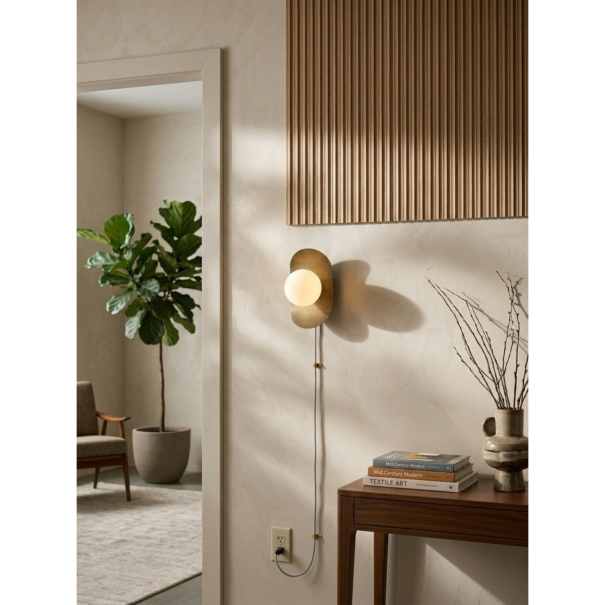Angled view of the brass Nouvel Wall Sconce against a dark wall.
