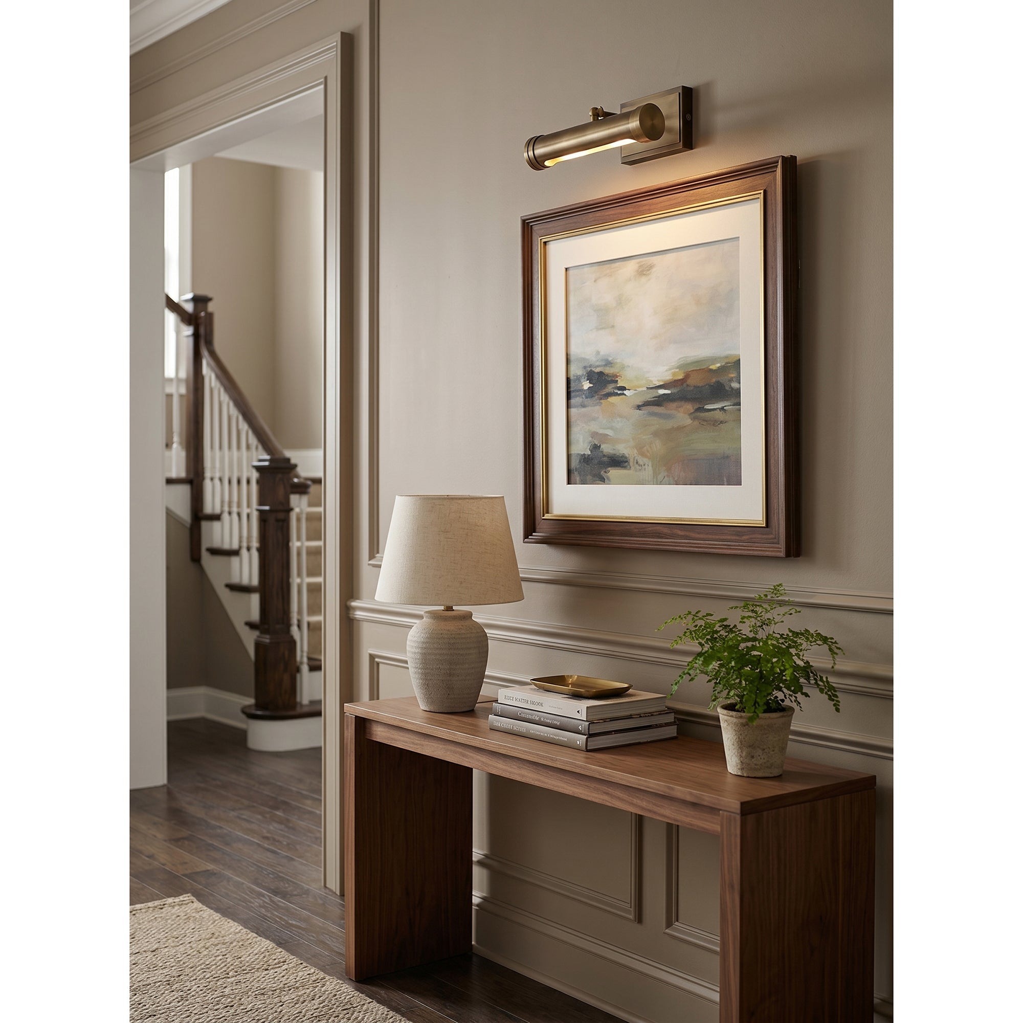 The Ridgewood Wall Sconce mounted in a hallway to illuminate artwork.