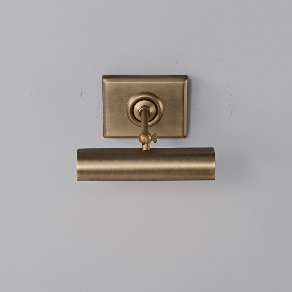 The antique bronze finish of the wall sconce against a dark wall.
