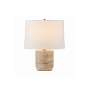 Toby Travertine Table Lamp with its fabric shade lit, showcasing its warm glow.