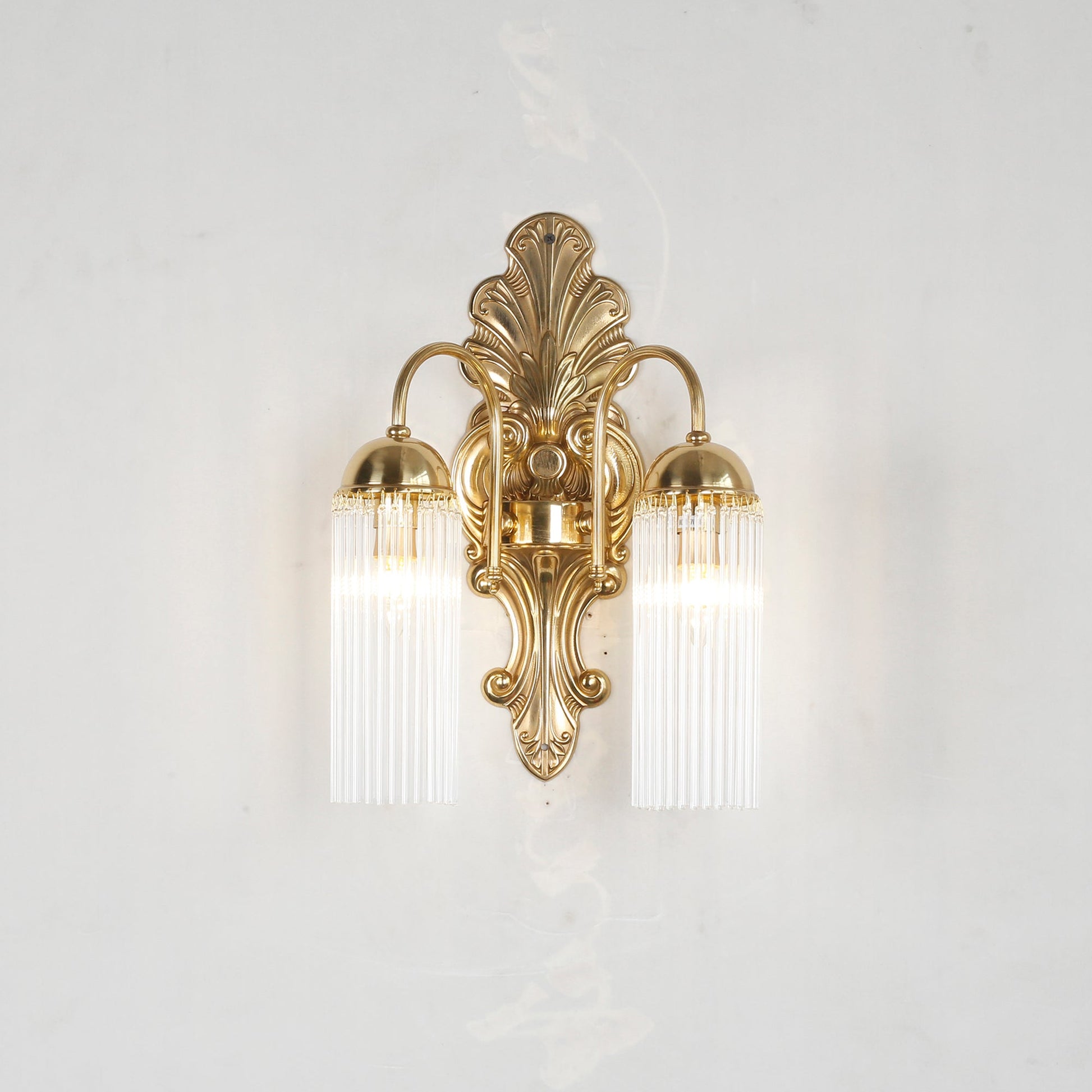 The Triest Wall Sconce against a dark wall to showcase the brass finish.